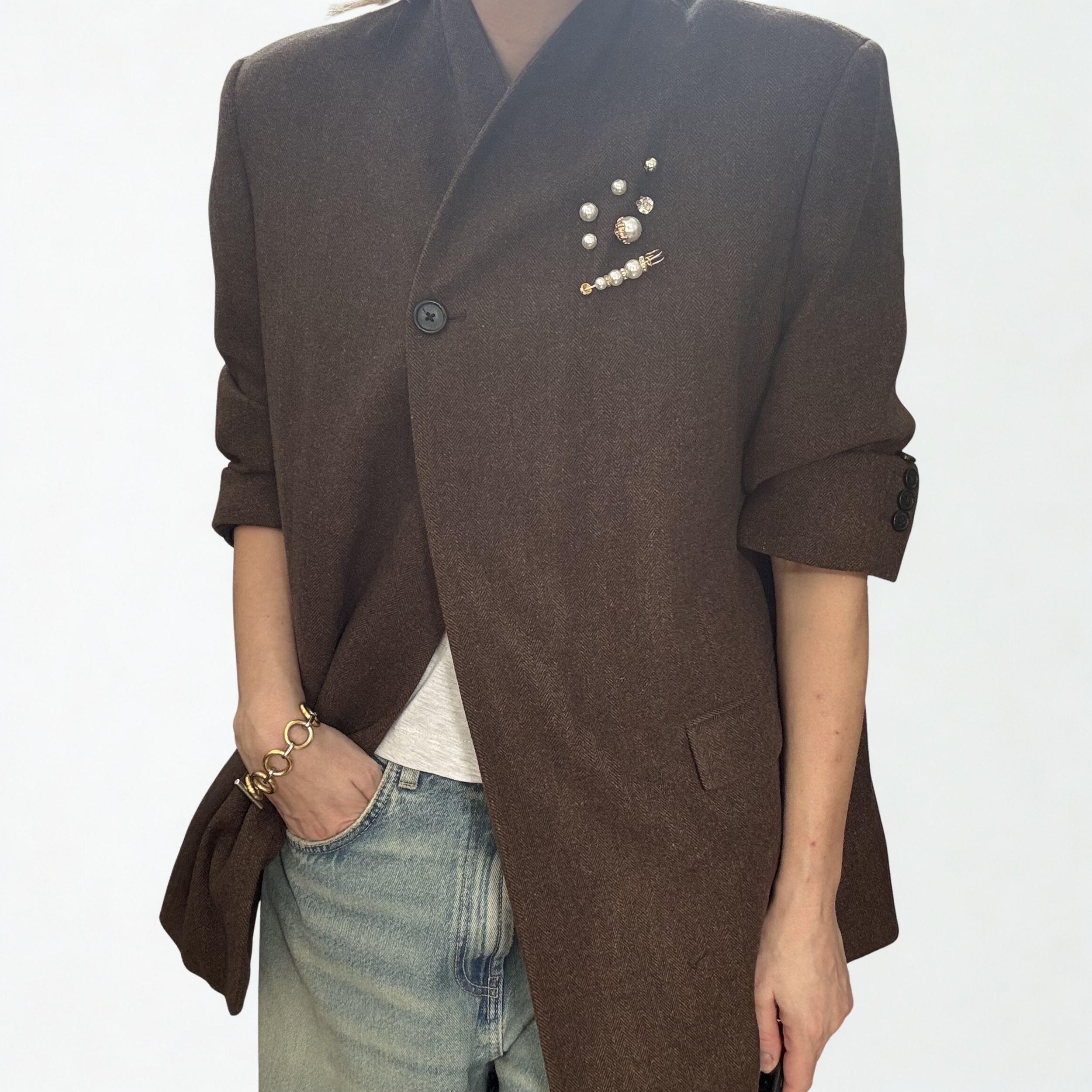 A cluster of pearl and gold brooches on the lapel of a woman's blazer.