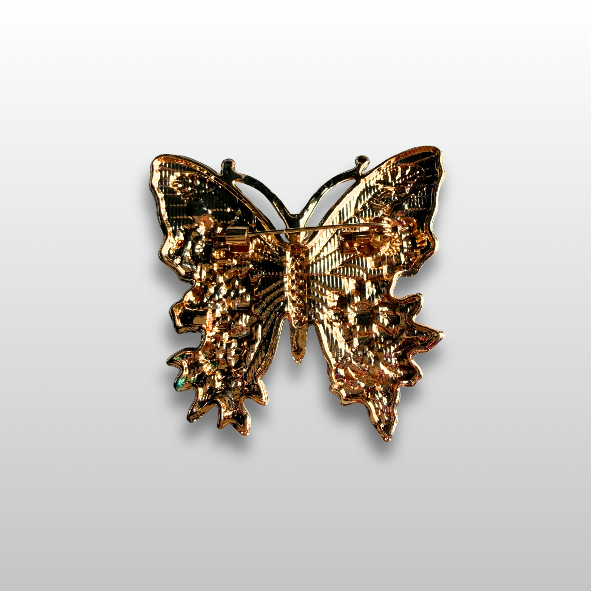 The backside of the butterfly brooch showcasing a traditional brooch pin closure.