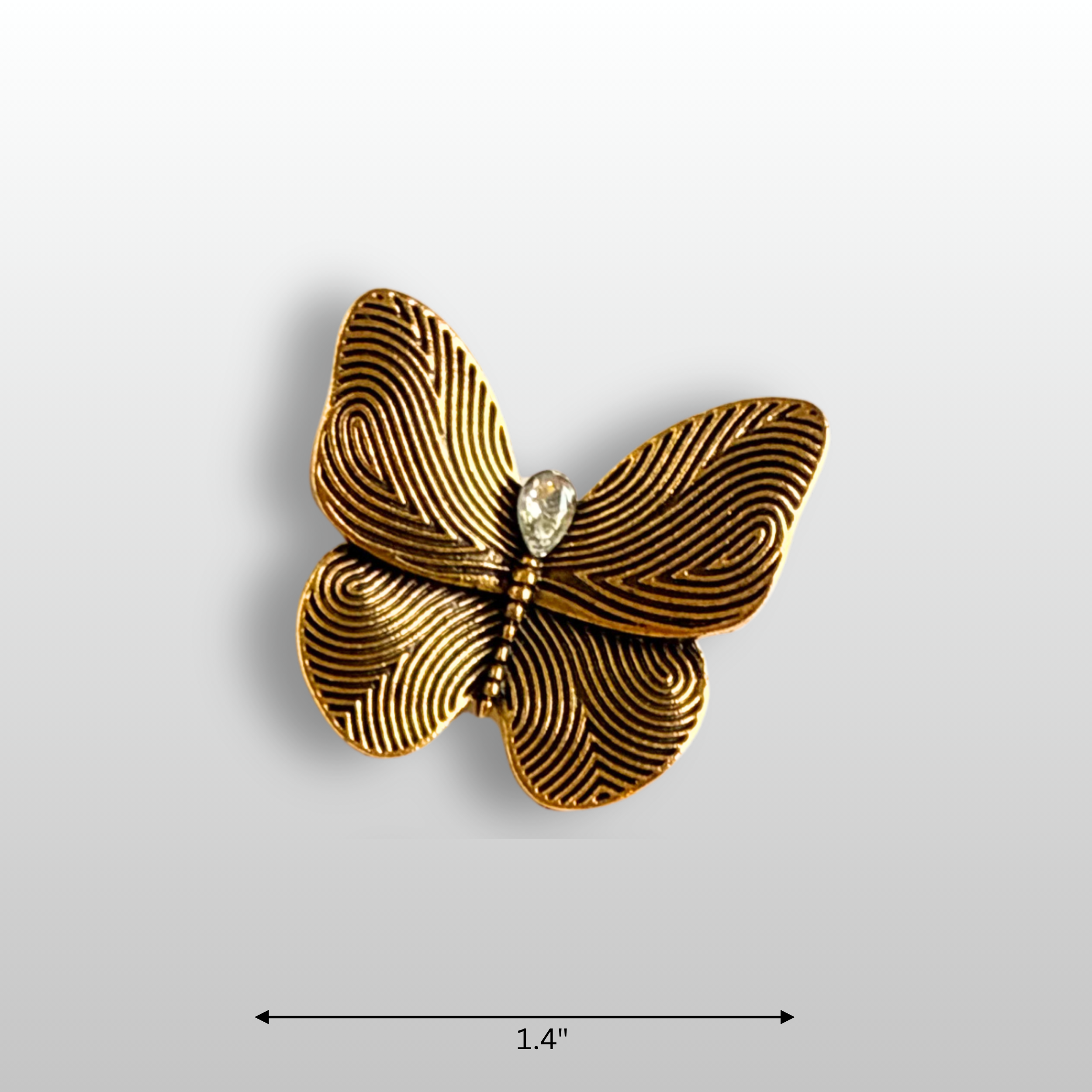 Close up of small golden butterfly brooch, with a small teardrop glass crystal in the centre.