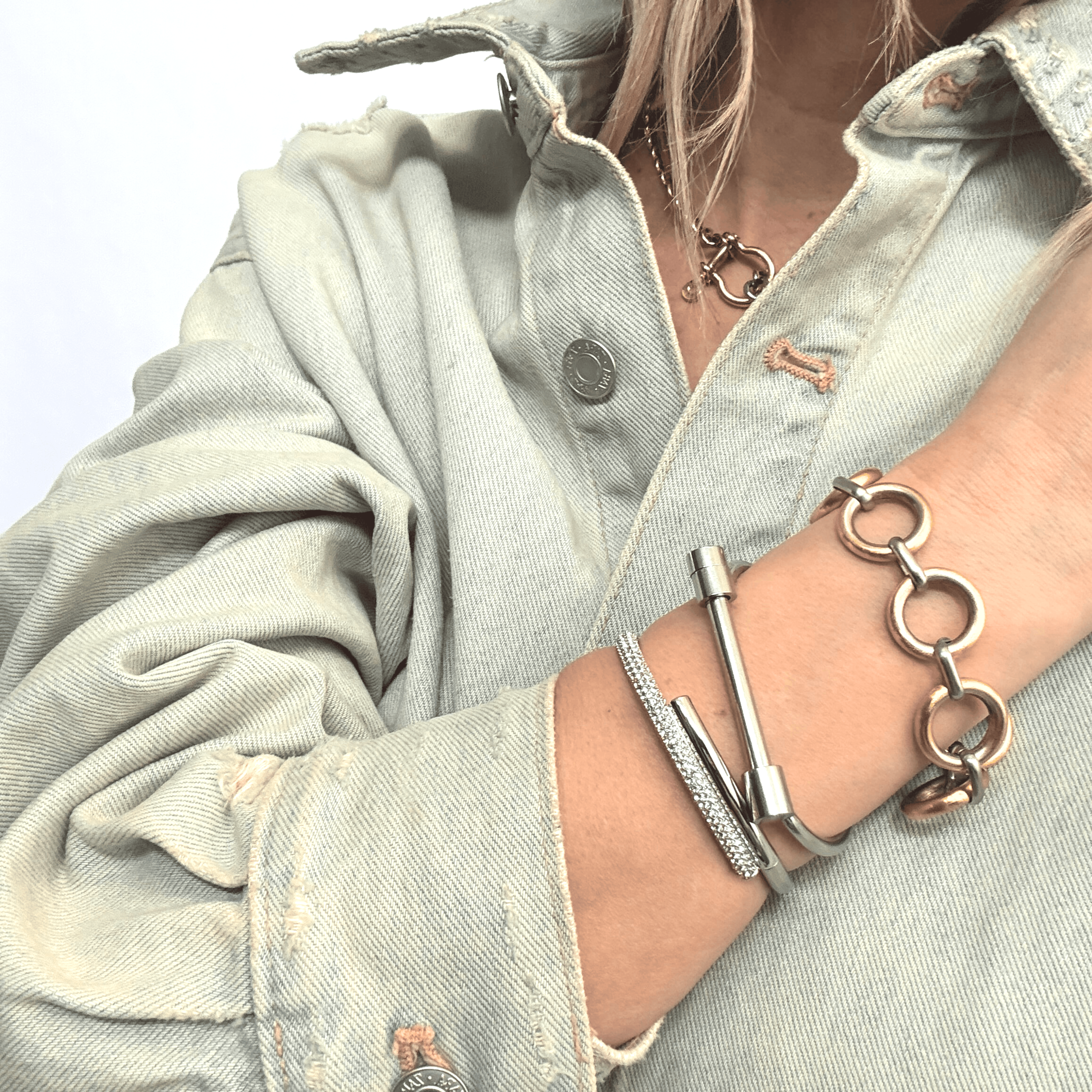 Stainless steel bangle with screw bar closure, styled with mixed metal bracelet stack and denim shirt.