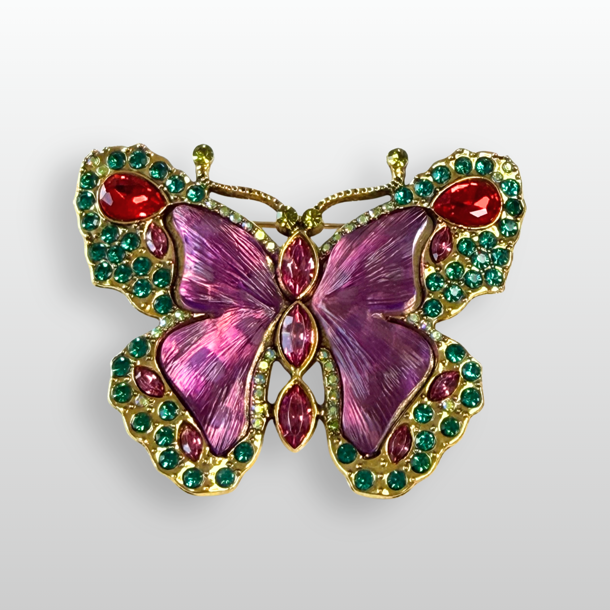 A close up of a purple and green gem encrusted butterfly brooch from The Brooch House.