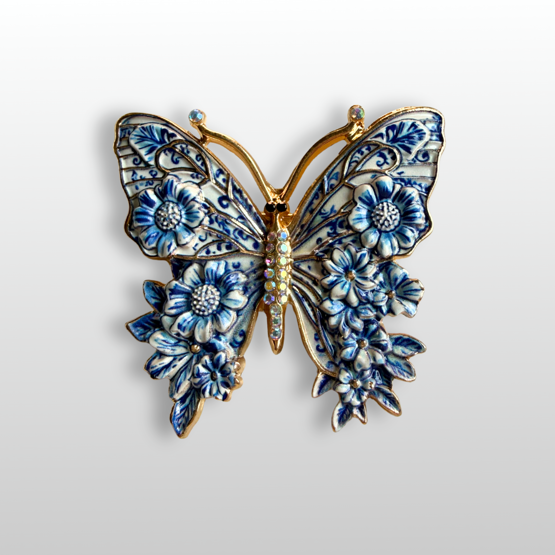 Close up of the Delft Monarch blue and white butterfly brooch with floral enamel, inspired by classic Delft porcelain patterns.