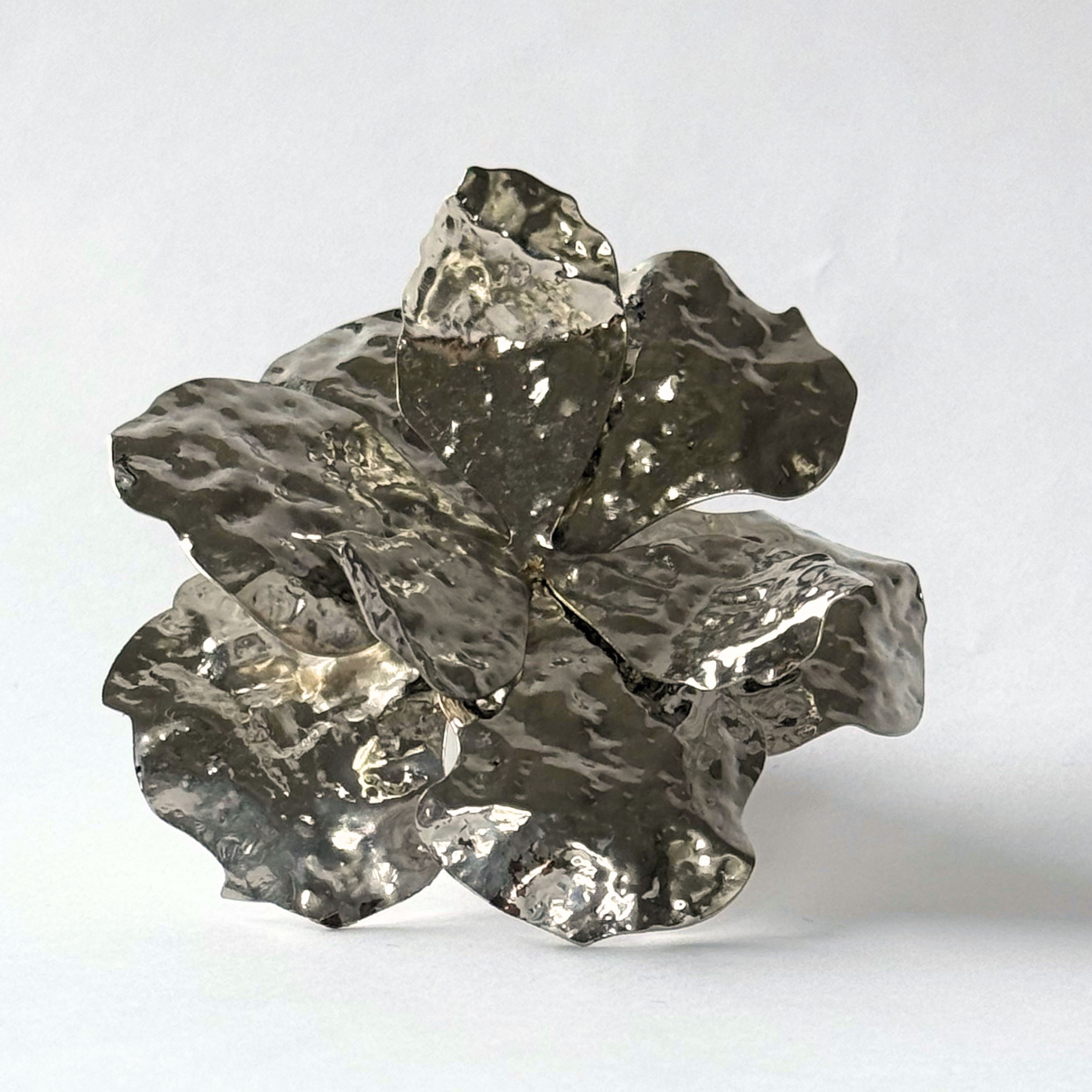 Close up shot of the magnetic hammered petal brooch in silver.