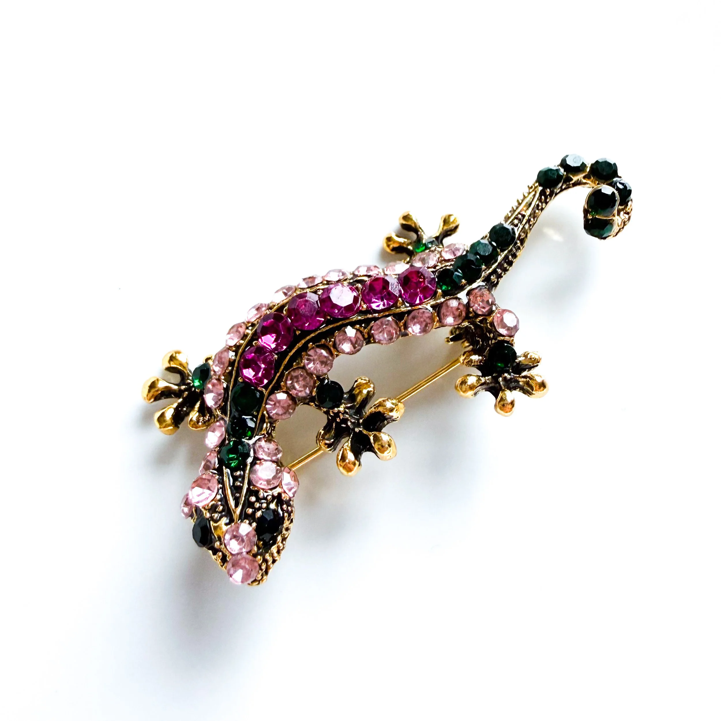 A close up of The Kaleidoscope Climber Brooch, a jewel toned gecko shaped brooch in a gold toned setting.