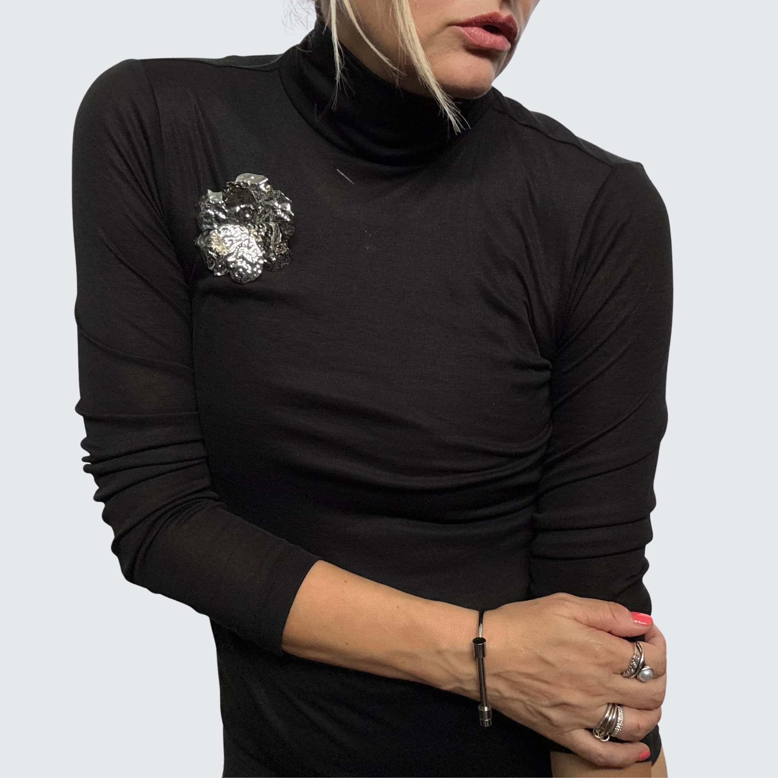 Woman wearing a black long sleeved fitted t-shirt styled with a silver hammered metal brooch from The Brooch House.