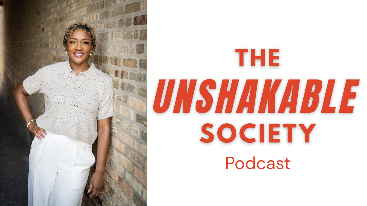 A smiling woman with short curly hair stands in front of a brick wall, wearing a beige short-sleeved sweater and white pants, next to text that reads 'The Unshakable Society Podcast'.