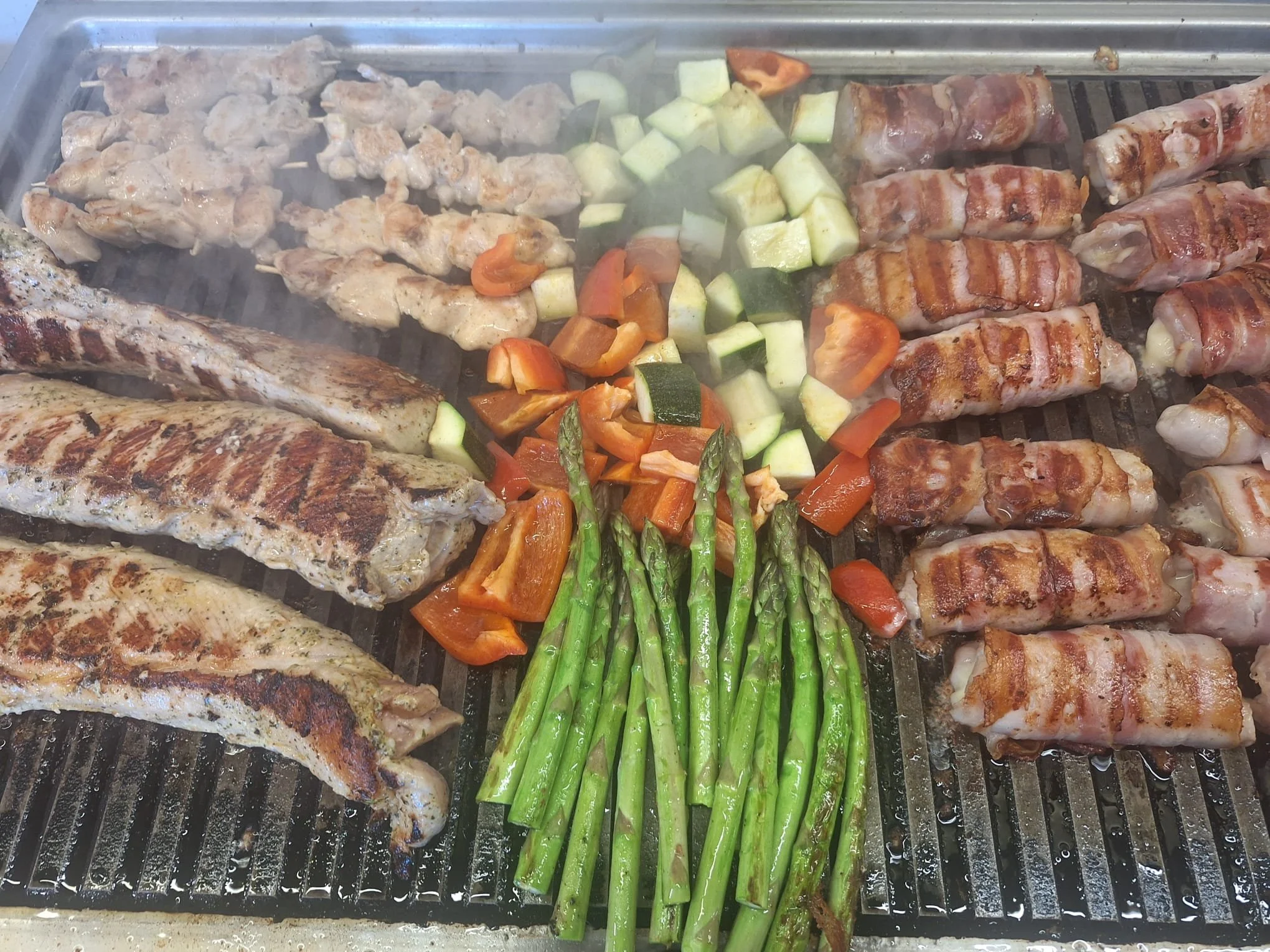 Grilling assorted meats, vegetables, and asparagus on a barbecue grill.