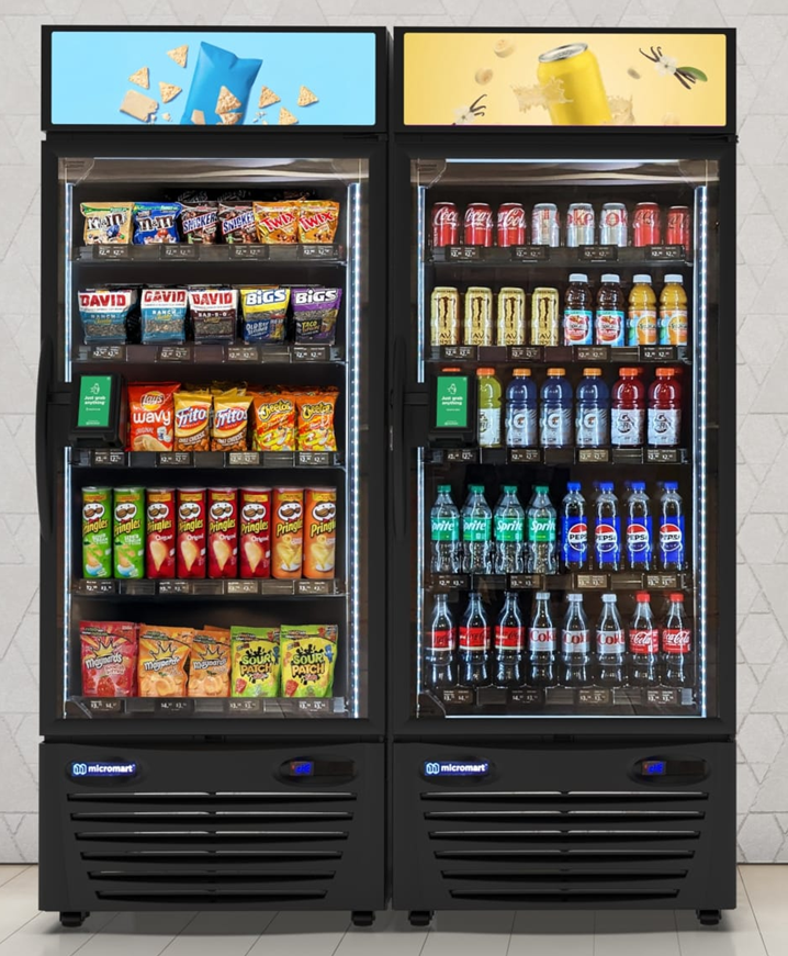 Two refrigerated vending machines filled with snacks and beverages. The left machine contains chips, candy, and granola bars, while the right machine has sodas, bottled water, and sports drinks.