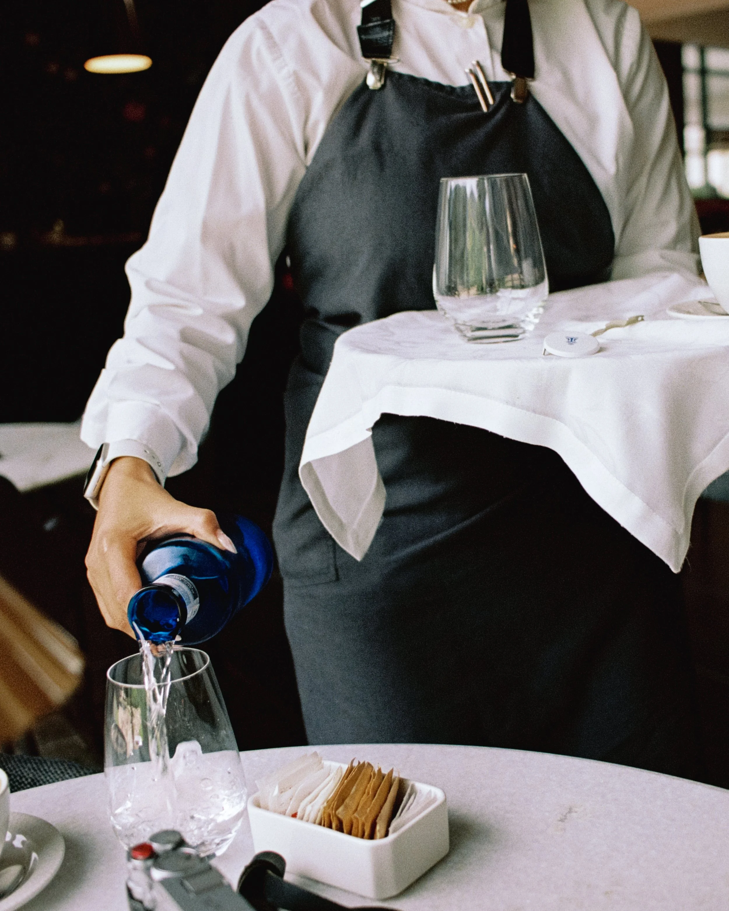 Un camarero sirviendo agua en un vaso en un restaurante