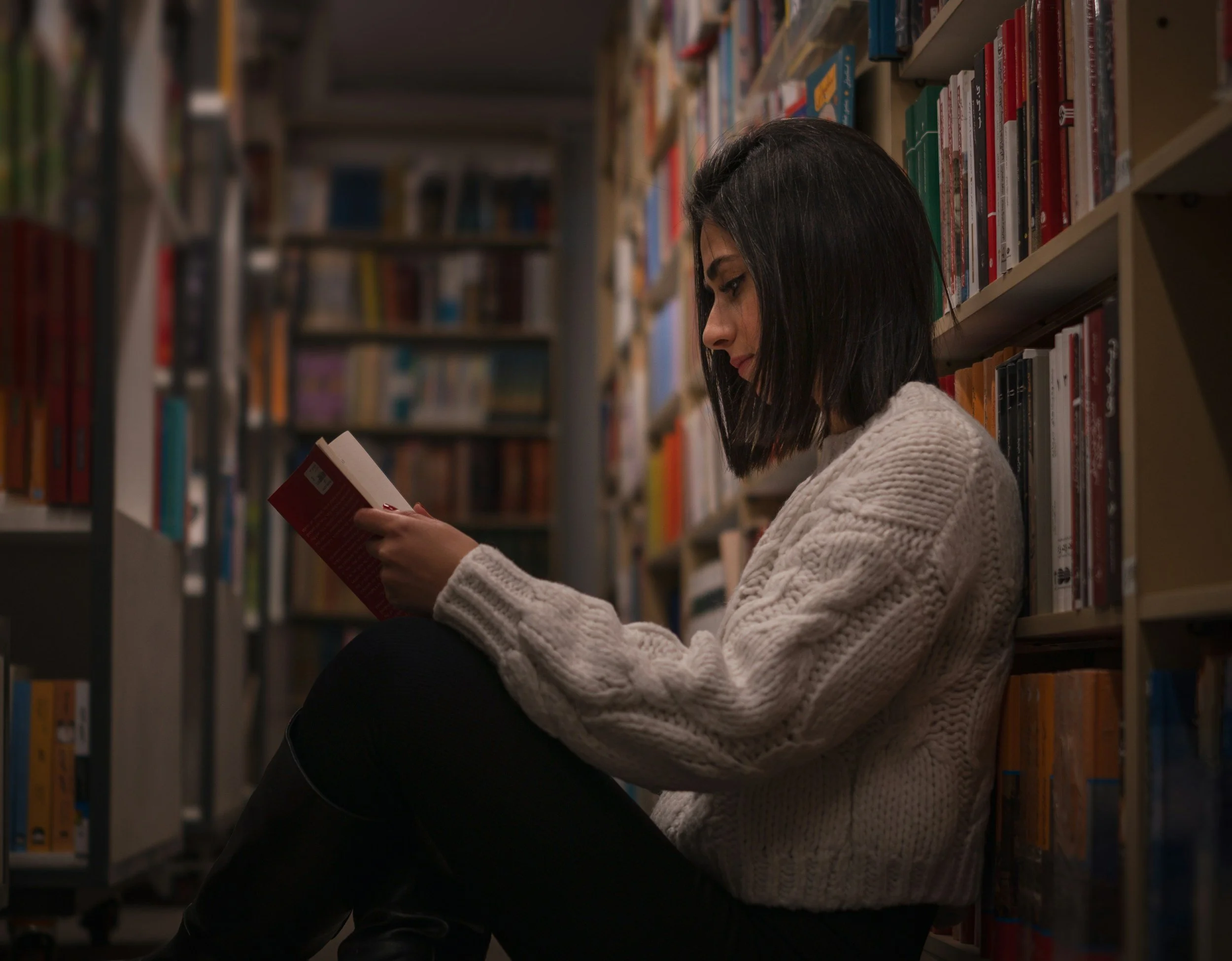 woman sitting in college library reading a book