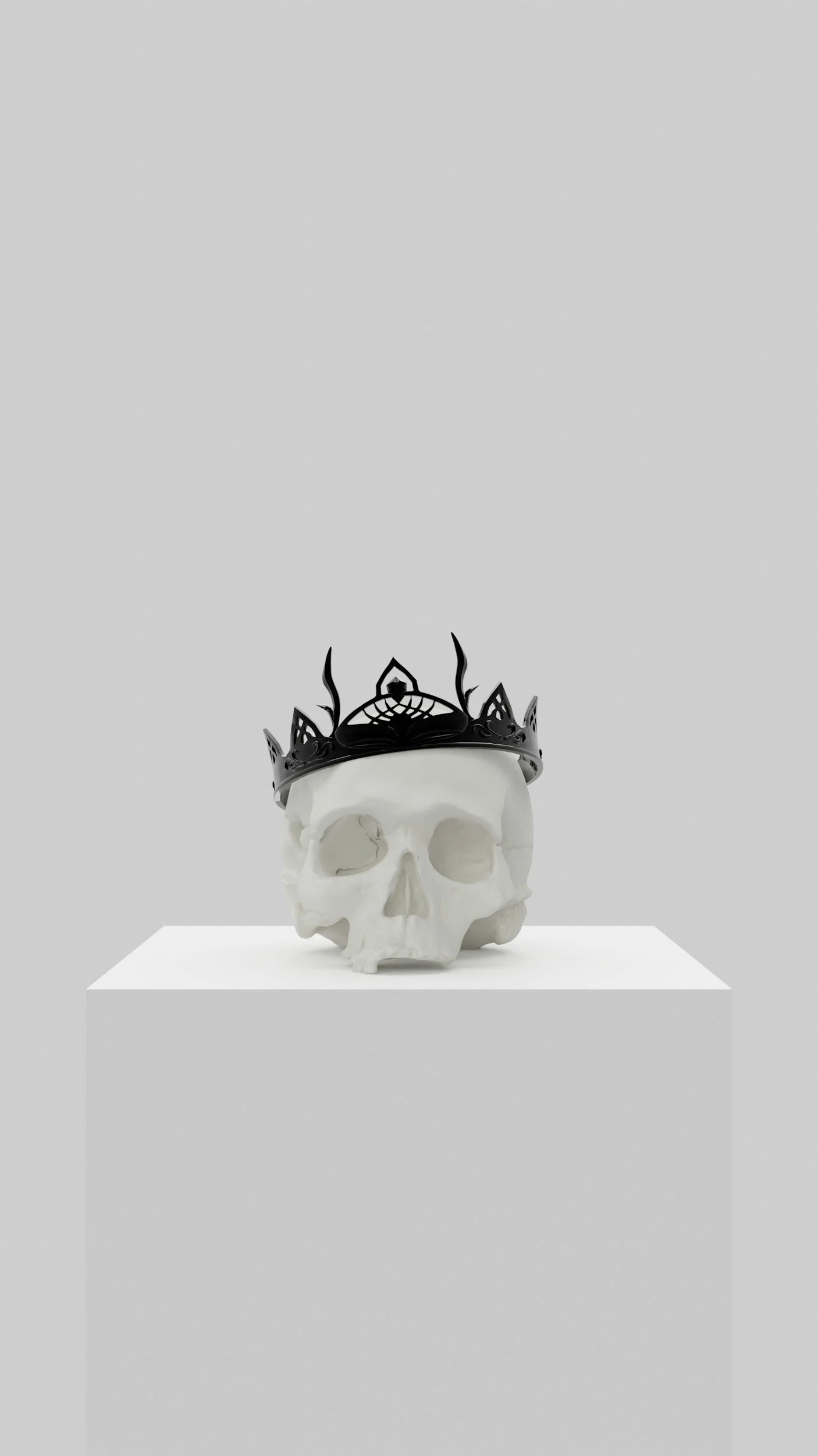 A white skull with a black crown on top, displayed on a white pedestal in a minimal gallery setting.