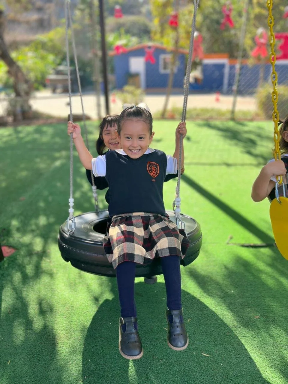 Niña feliz en un columpio de neumático en un parque infantil.