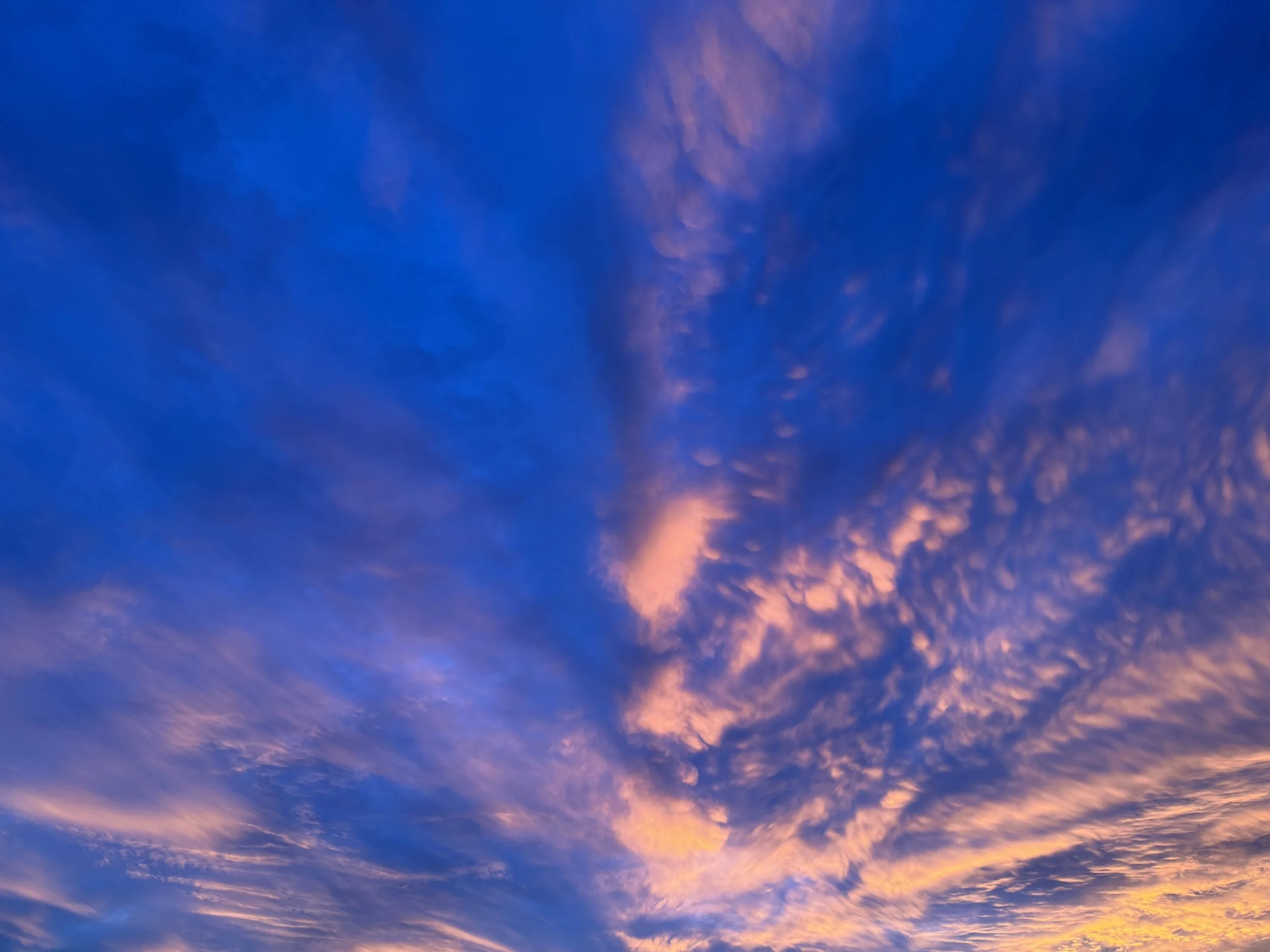 A scenic sky with a mix of blue, purple, and orange hues during sunset or sunrise, with wispy clouds.