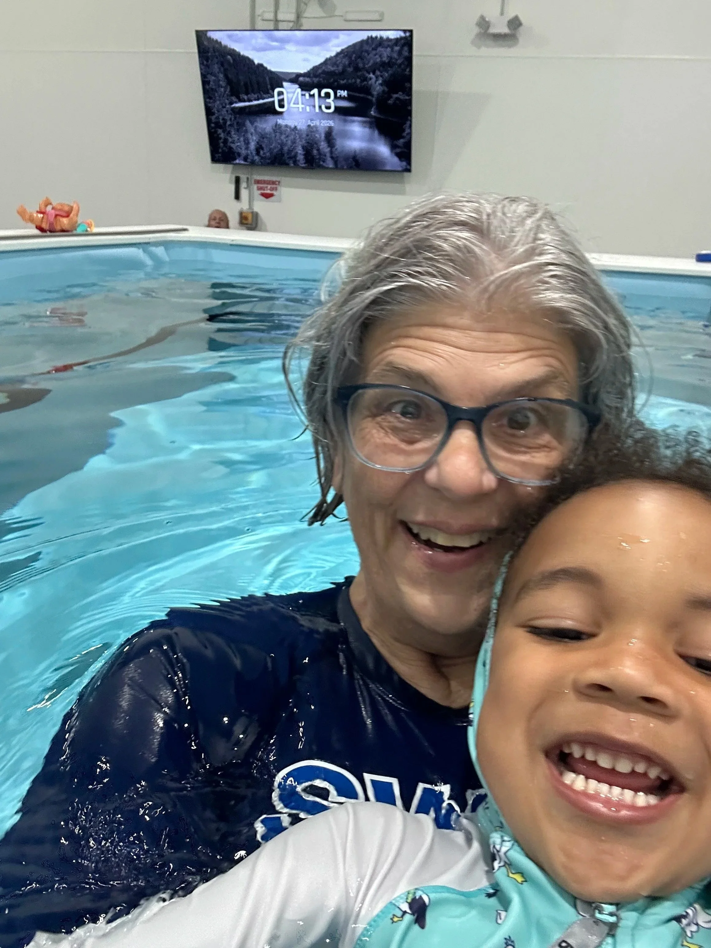 Cathy Sheafor in navy shirt in the pool with a young child. 