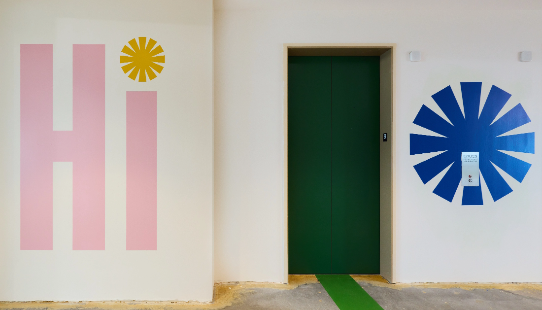 Hi wall in entrance elevator bank on leasing floor with green door floor graphics and pink hi wall graphic