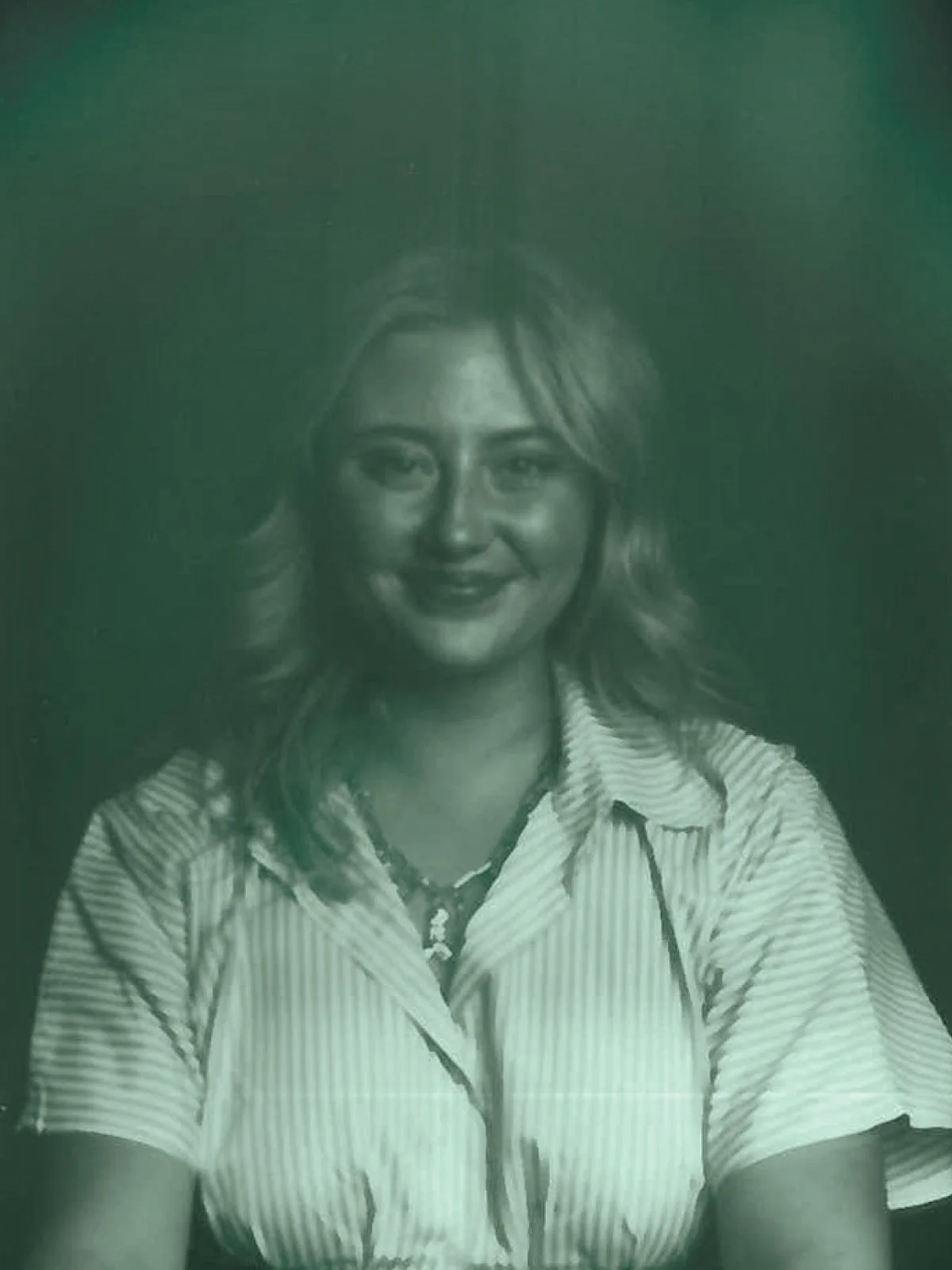 Hailey Markovsky, Black and white portrait of a smiling woman with shoulder-length wavy hair, wearing a striped shirt and a necklace.