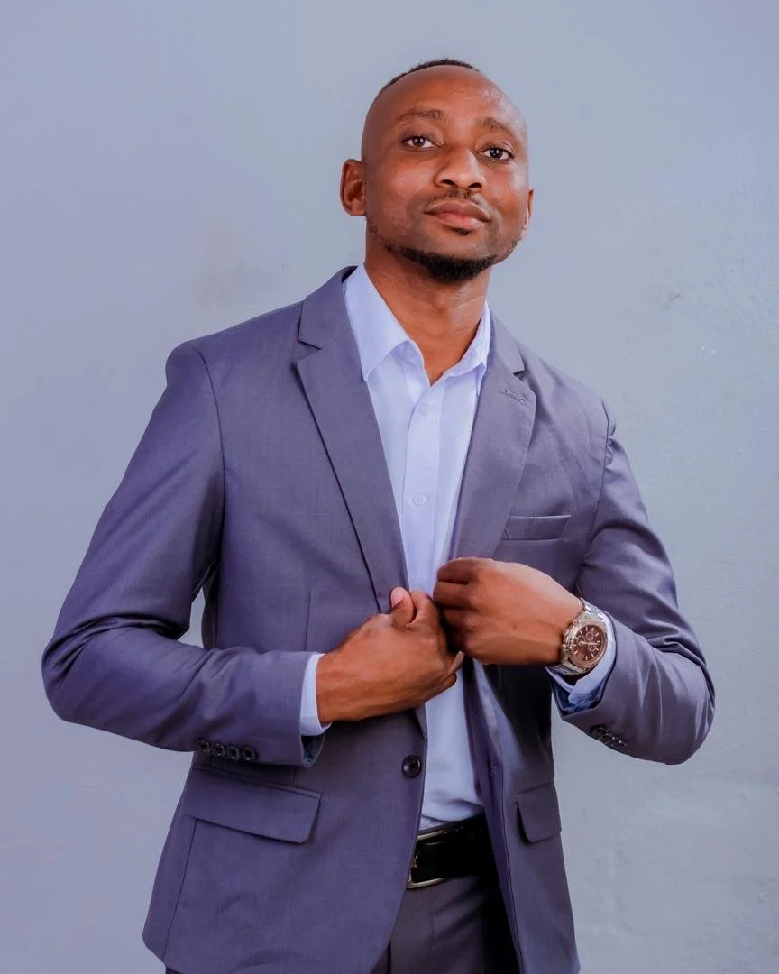 A woman with glasses and hoop earrings smiling, wearing a striped shirt, in what appears to be an indoor setting.