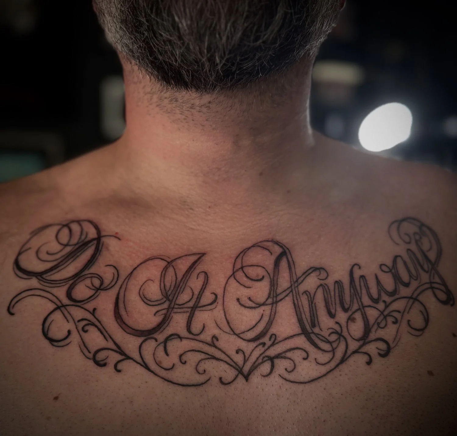 Tattoo on person's chest with the name 'Joe Armstrong' in ornate cursive script