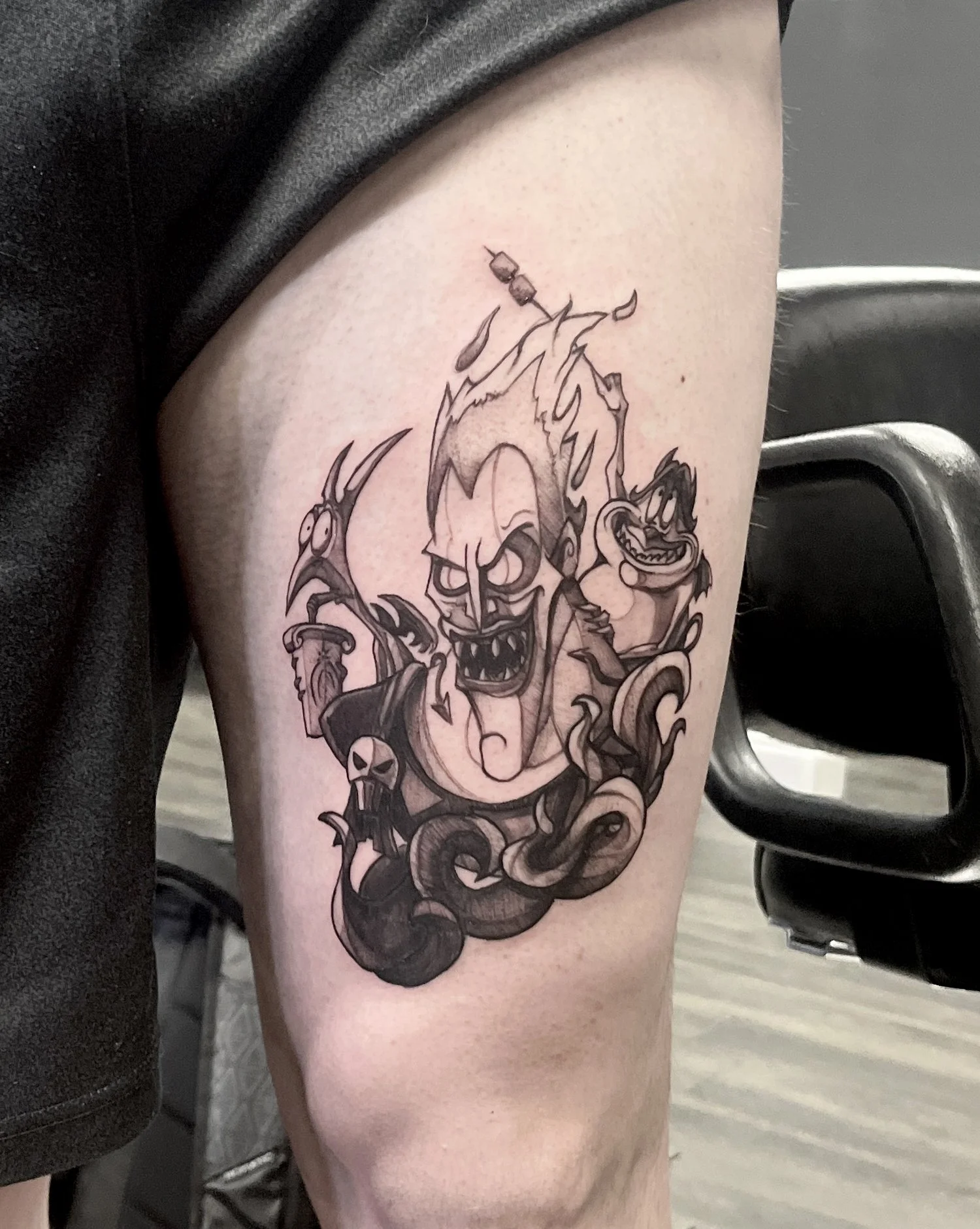 Tattoo of a cartoon character with spiky hair, sharp teeth, and an angry expression, surrounded by dark, smoky elements and other smaller cartoon characters.
