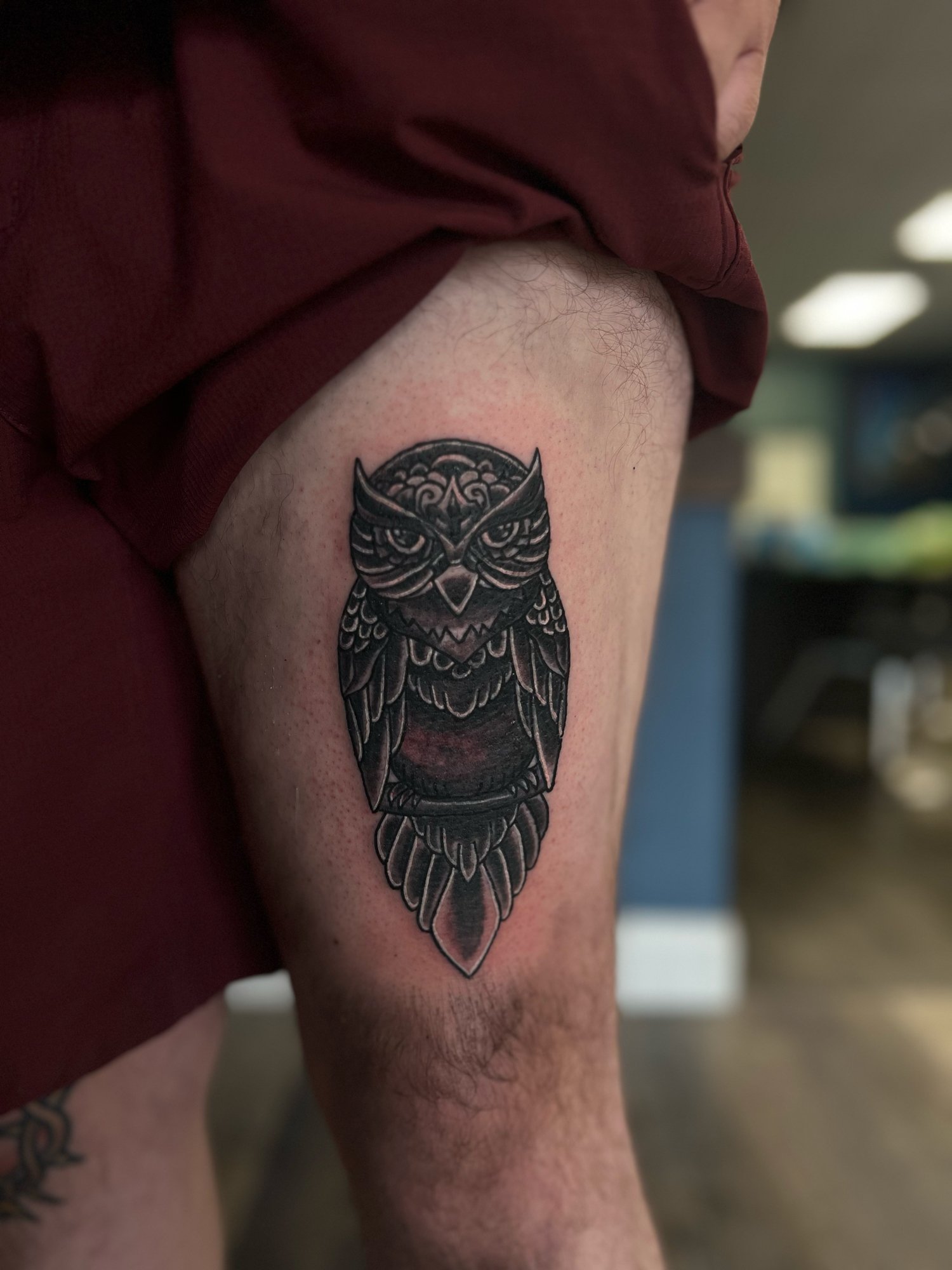 Black and gray owl tattoo on person's upper thigh.
