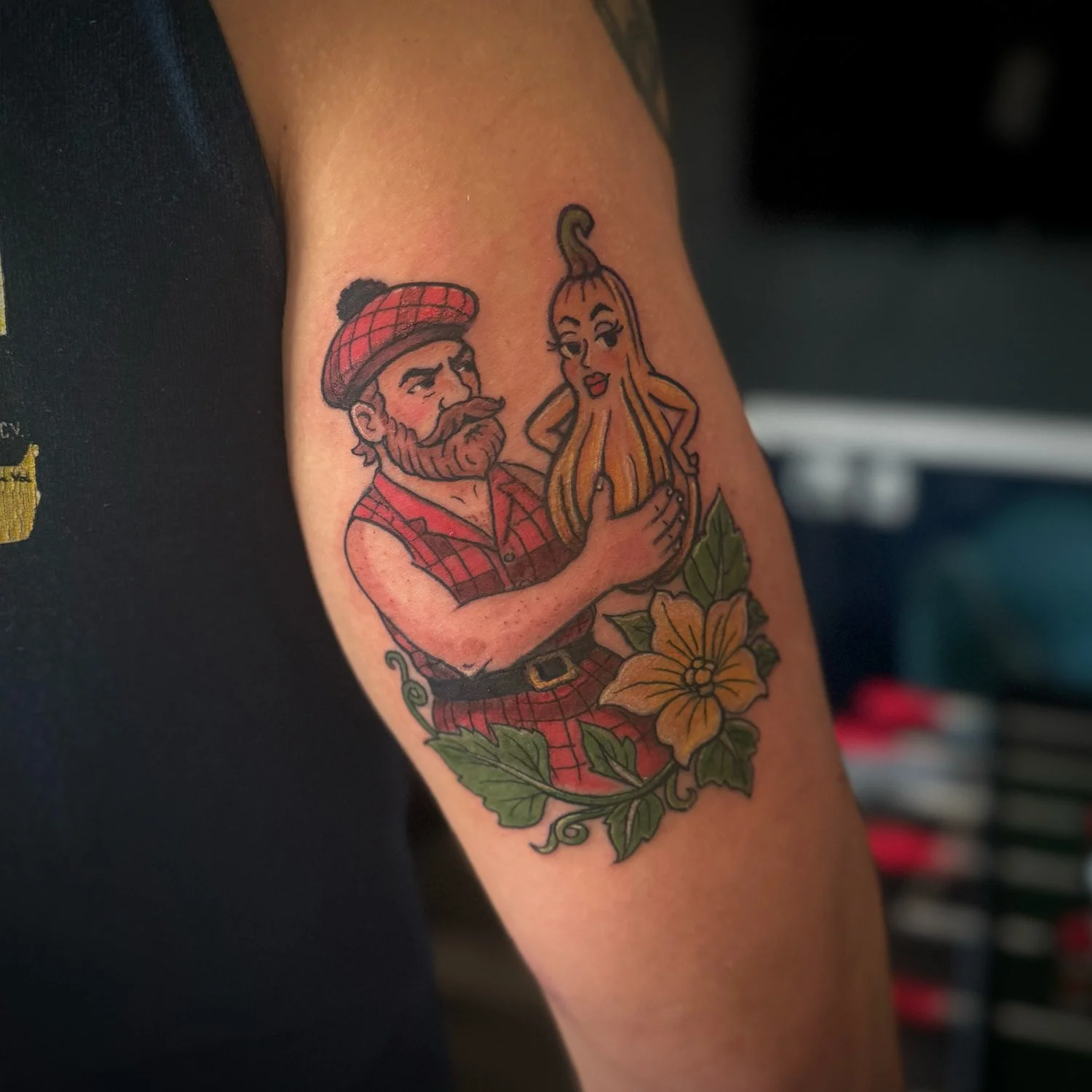 Tattoo of a bearded man in Scottish attire holding a woman-shaped onion on the arm, with floral and leaf elements at the bottom.