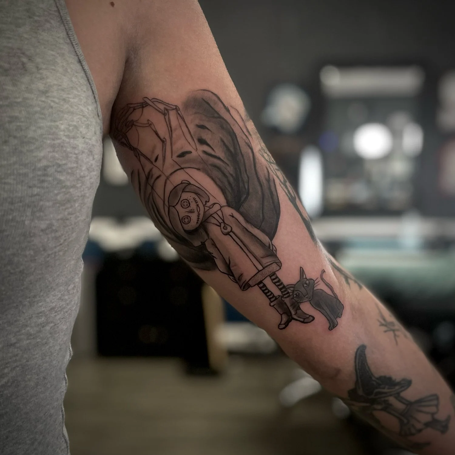 Tattoo of a cartoon girl with a doll on the person's arm.