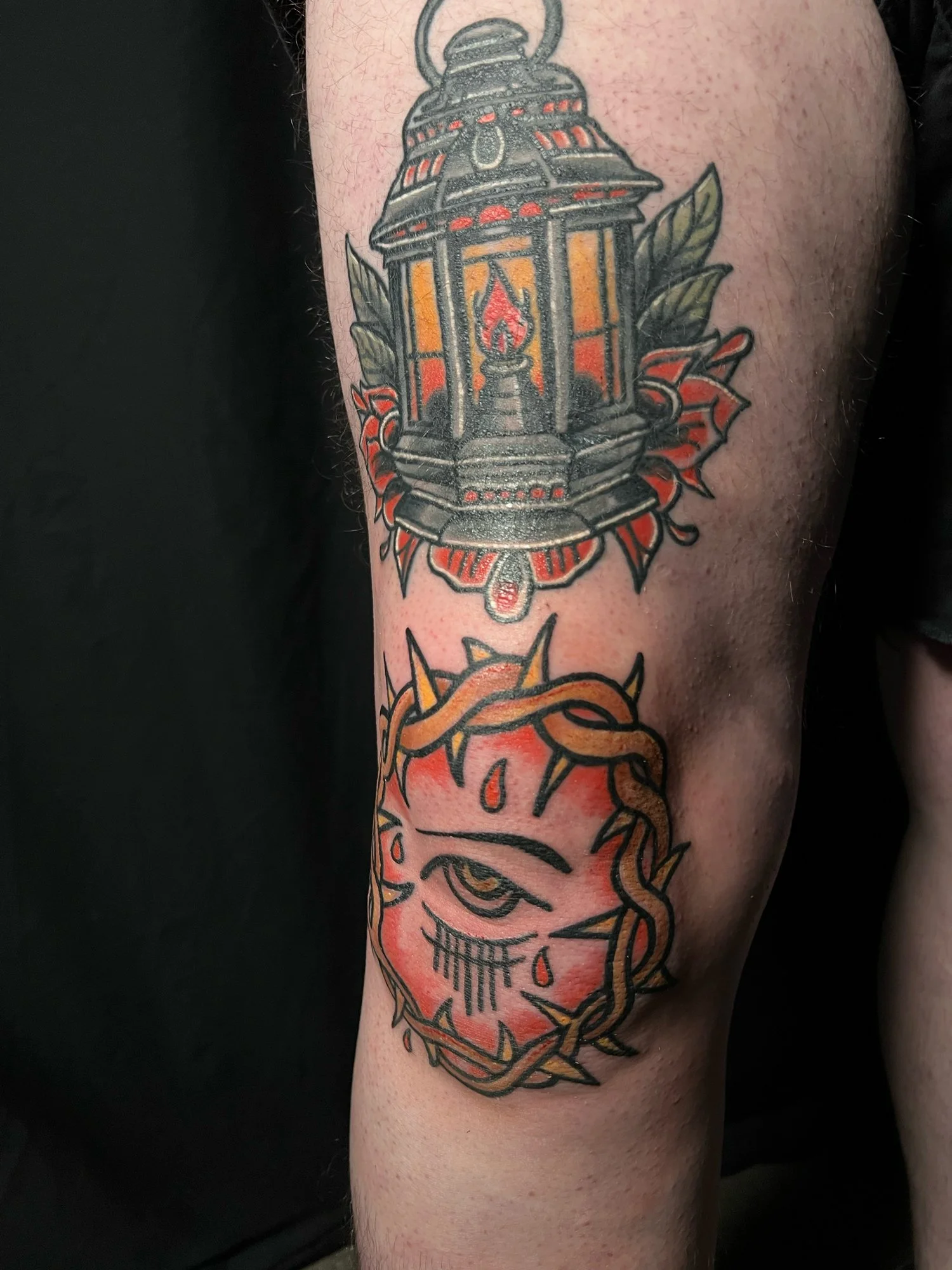 Tattoo of a vintage lantern with a candle inside and an eye with tears and a crown of thorns around it.