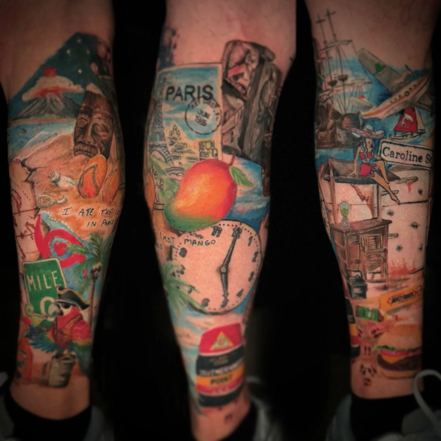 Colorful tattoos on arms depicting various scenes including a volcano, a skull, a peach, a clock, a lighthouse, a map, and other travel-related images.