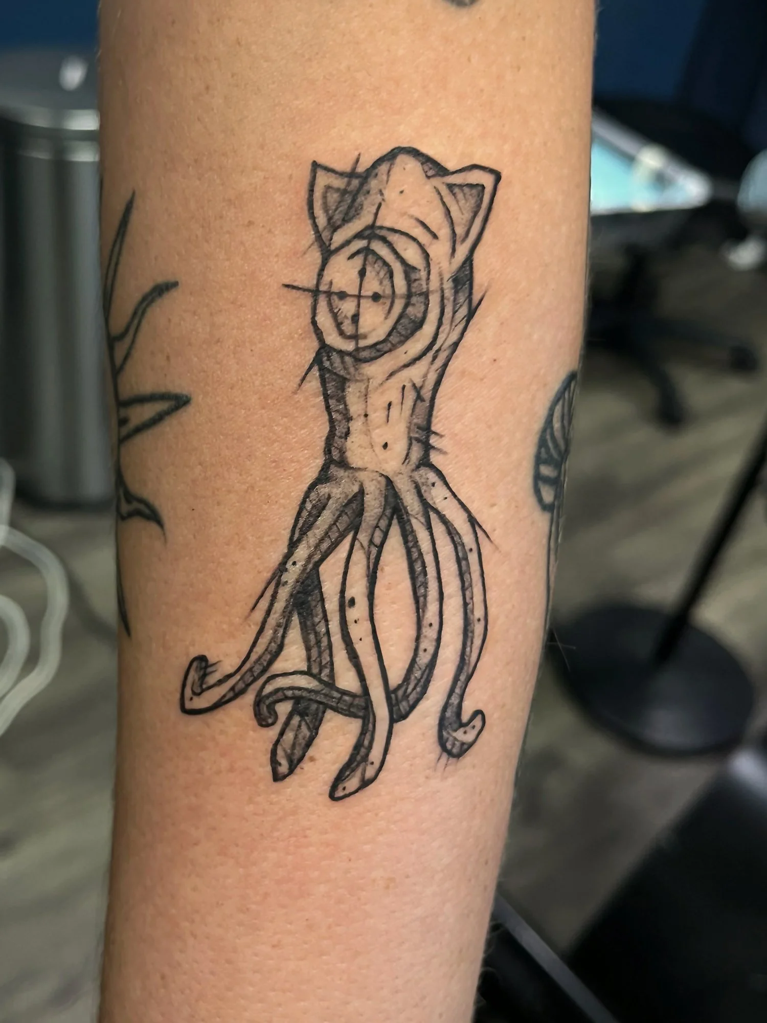 Tattoo of a tiger's face inside a crosshair scope, combined with an octopus body on a person's arm.