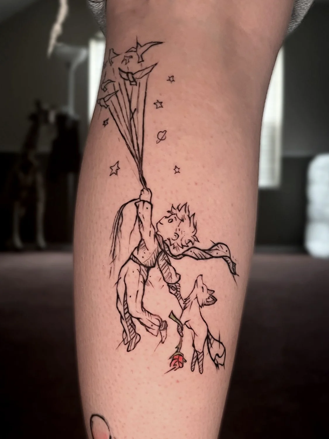 Tattoo of a young boy with spiky hair, holding a bunch of stars and planets, with a small dog on a leash, surrounded by stars and space elements.
