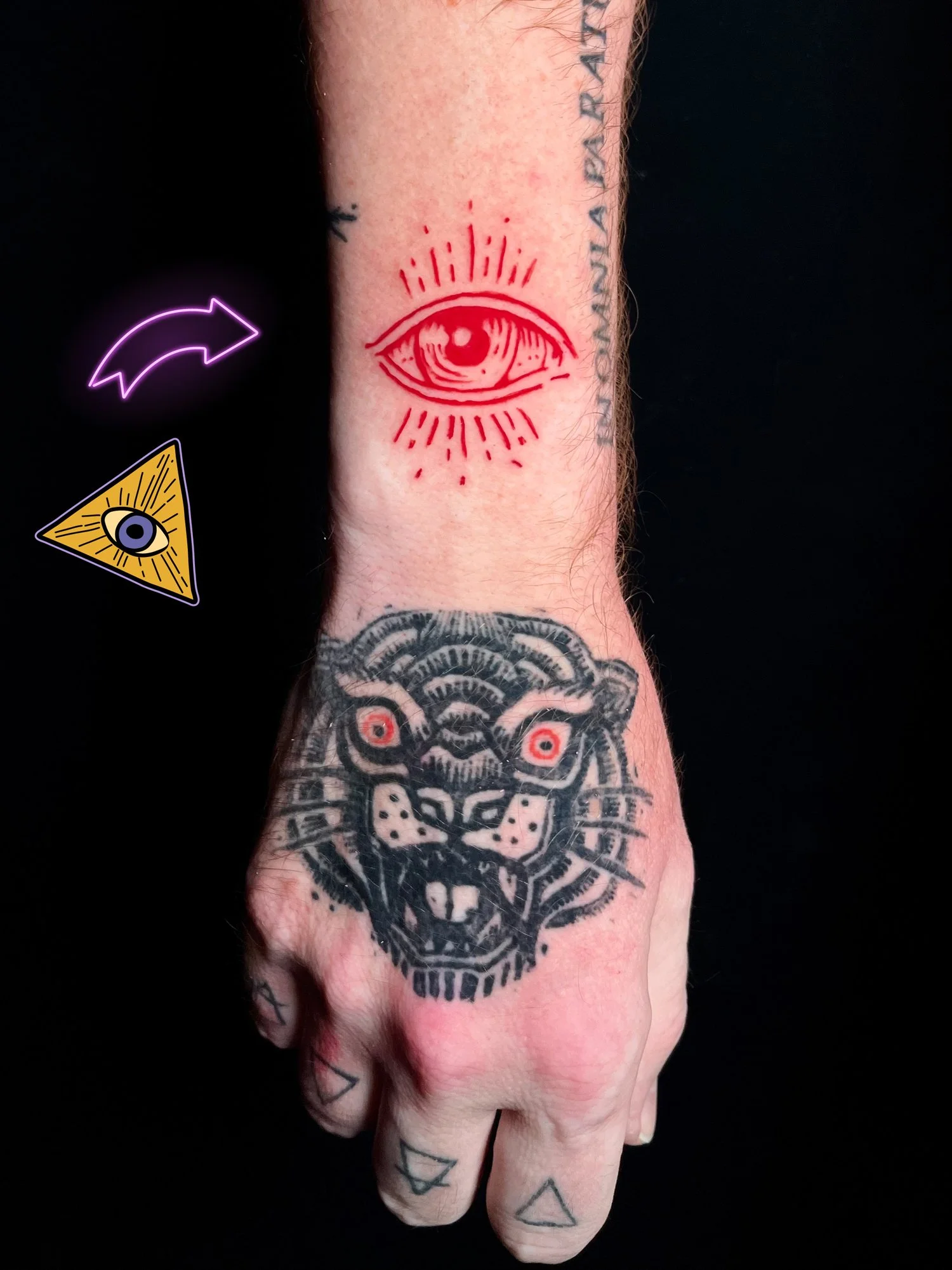 A person's hand with black tattooed tiger face on the back, and a red tattoo of an eye with rays above the hand. The hand has additional small tattoos on fingers and is set against a black background.