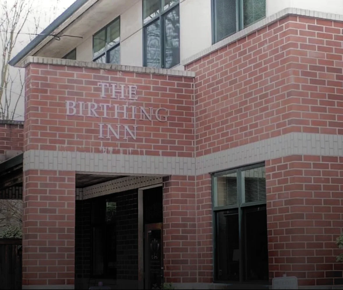 The exterior of The Birthing Inn's brick building with a sign reading 'The Birthing Inn' on a section of wall.