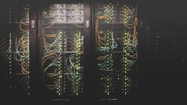 Server racks with illuminated network cables inside a data center.