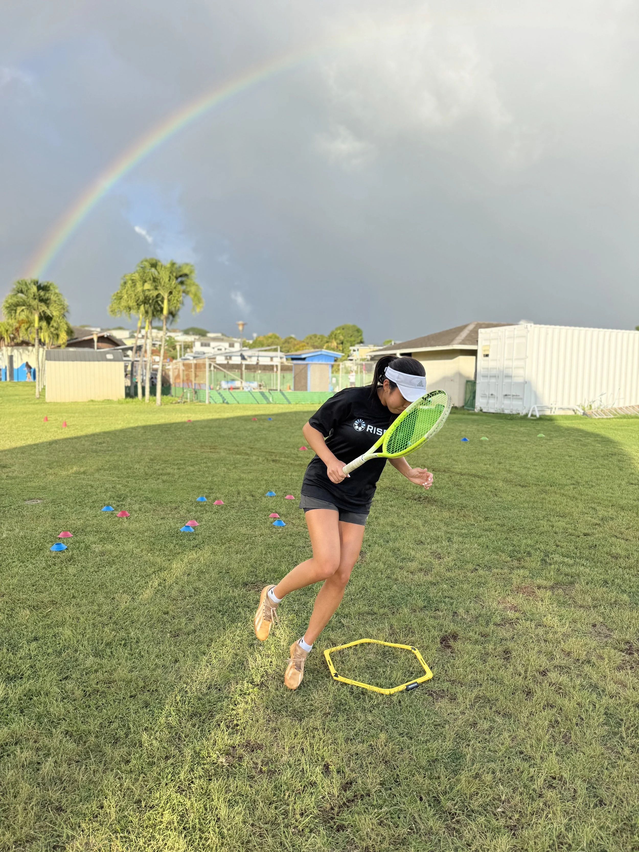 Tennis player doing agility at training with rainbow in background