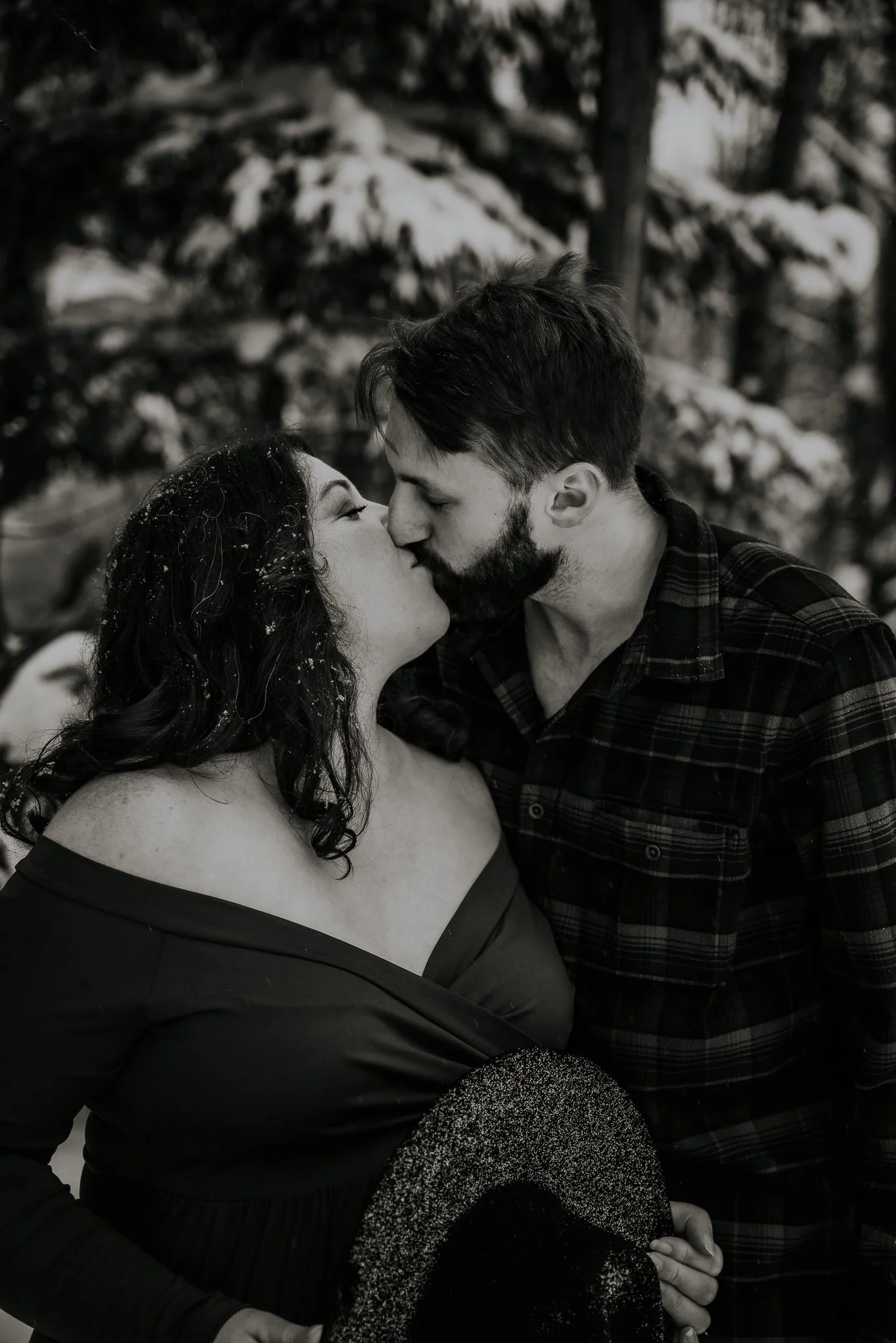 A couple kissing outdoors in a snowy landscape.