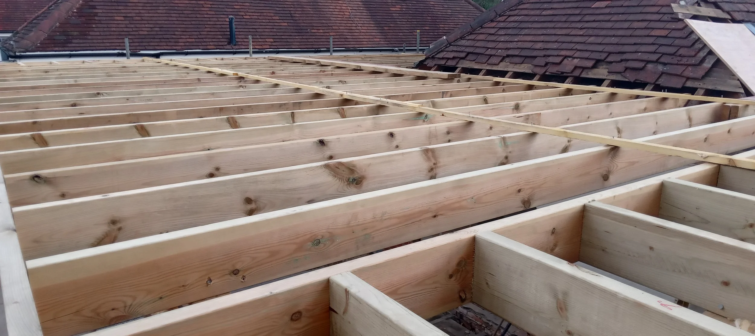 Wooden roof framework under construction with exposed wooden beams.