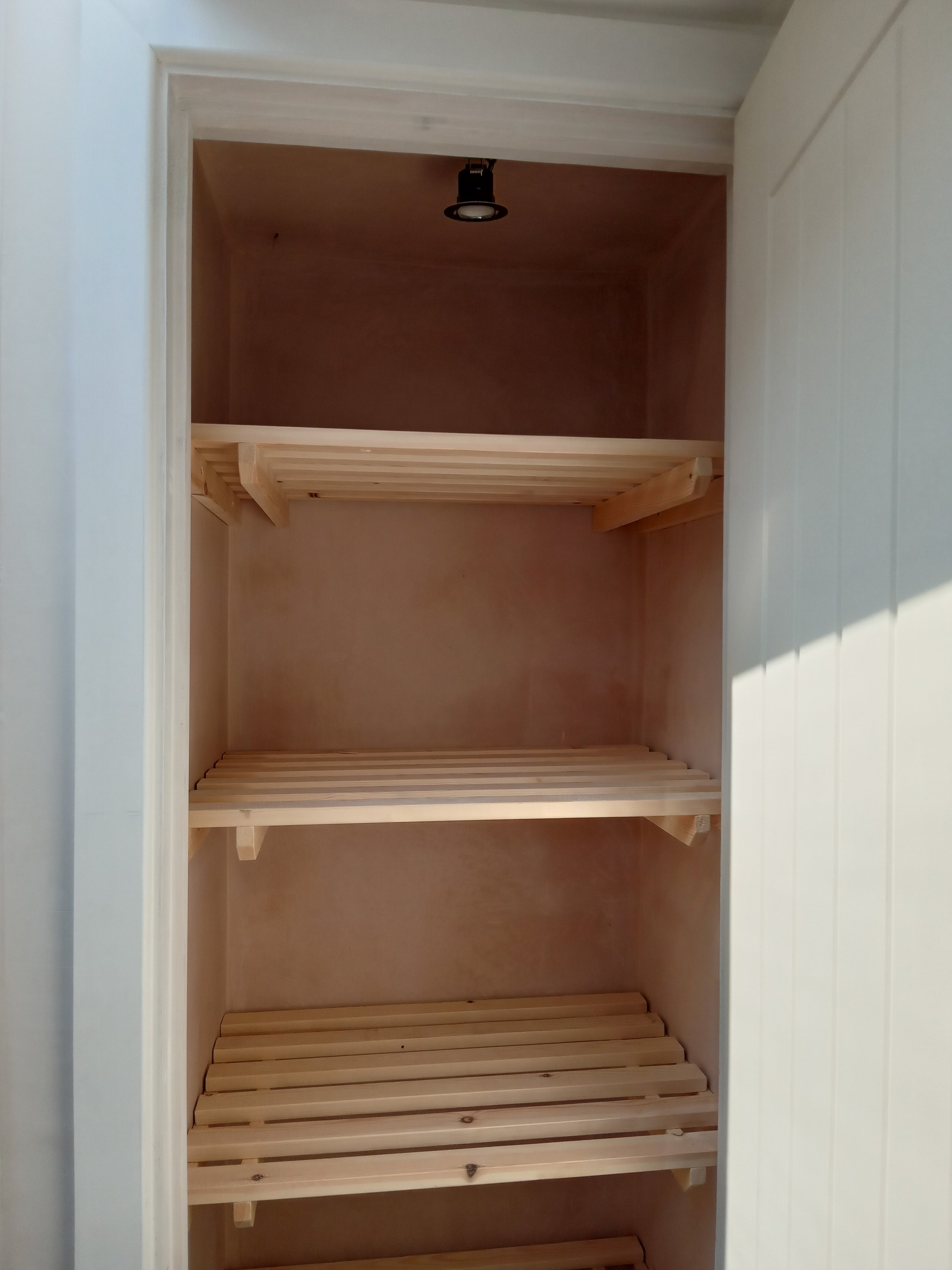 Empty wooden closet with multiple shelves inside a white frame.