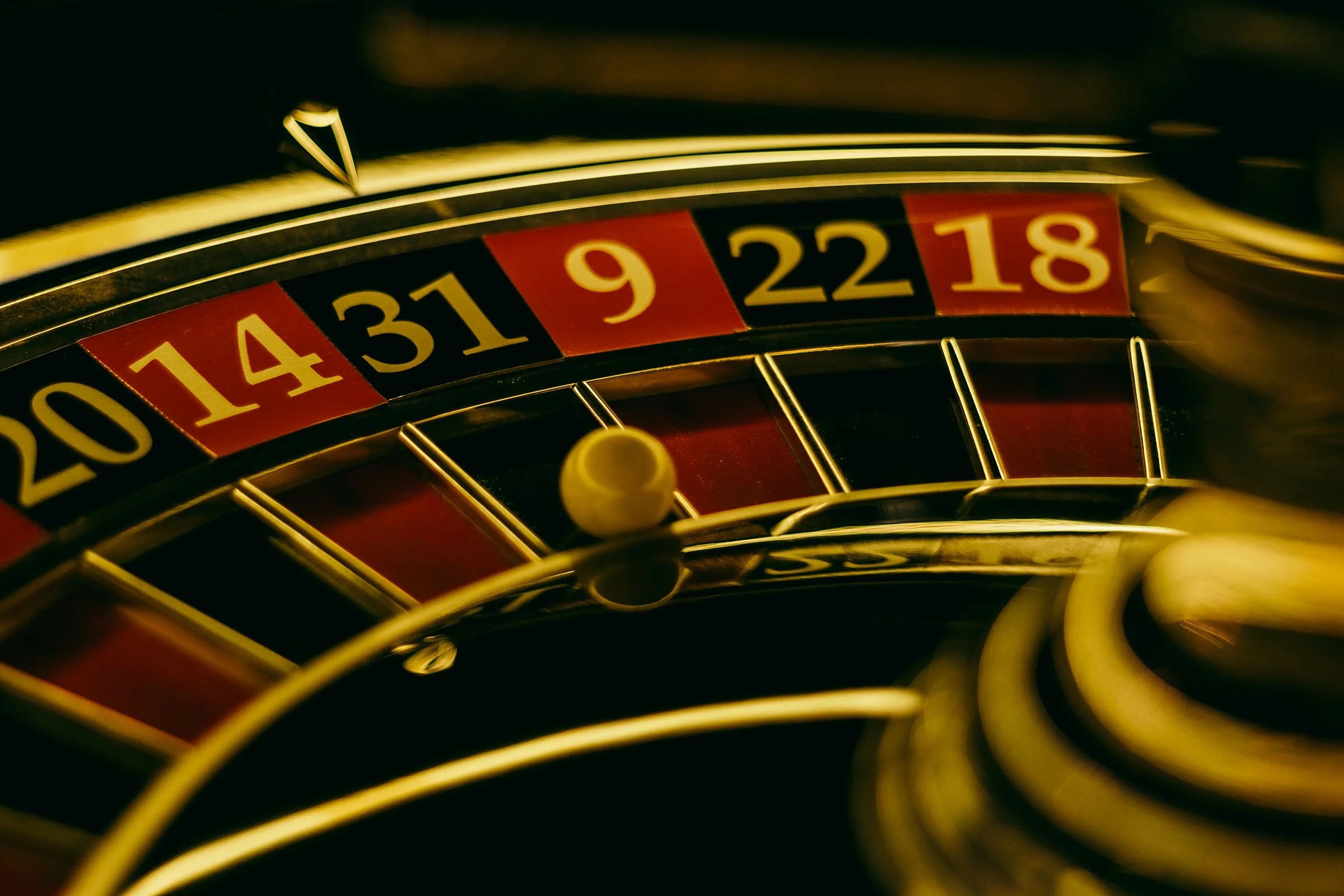 Close-up of a roulette wheel showing numbered pockets from 20 to 18, with a yellow ball resting on the wheel.