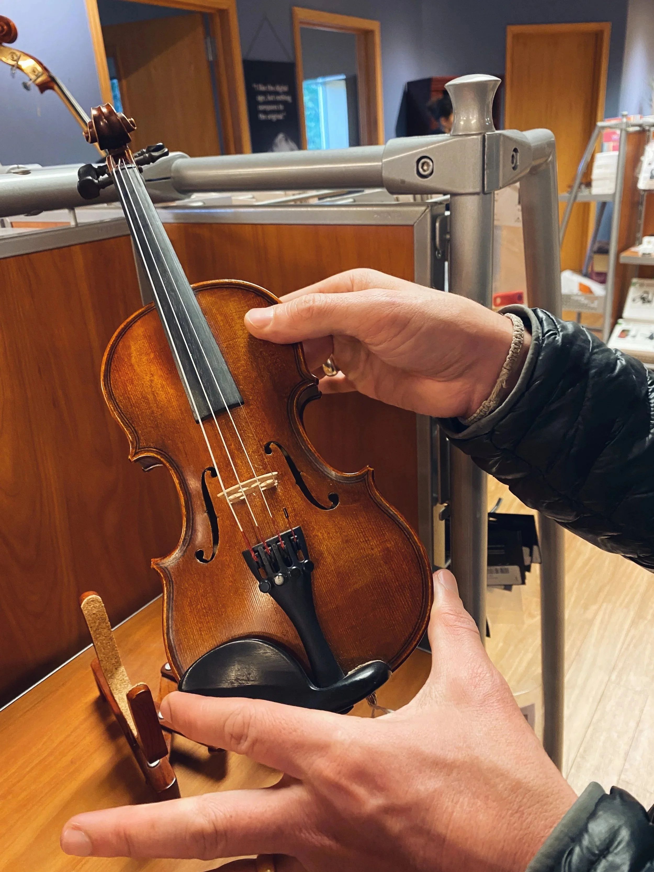 person holding a 1/16th size violin in Shure Violins Music Shop.