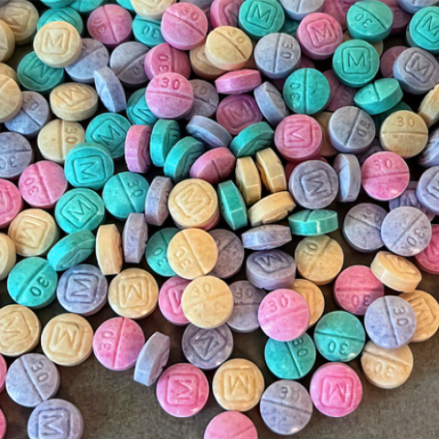 Colorful tablets in pink, yellow, purple, green, and blue scattered on a surface.