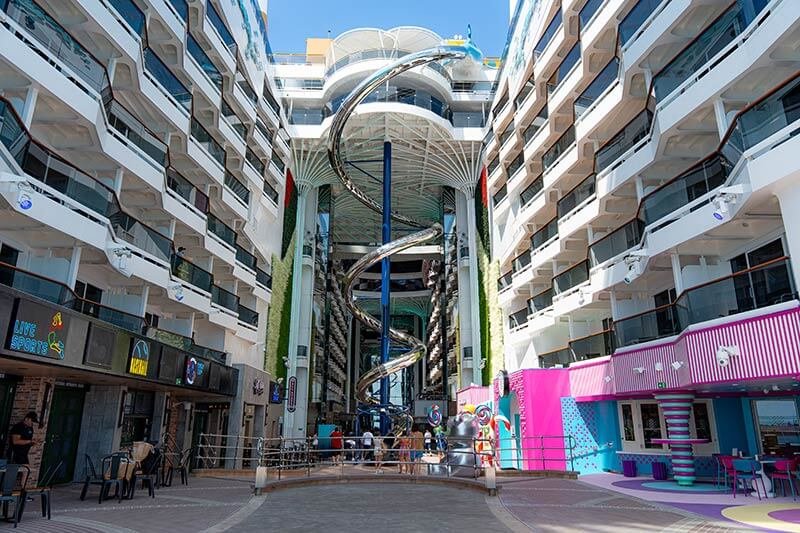 Indoor pool area on a cruise ship with a large spiral water slide and surrounding balconies.