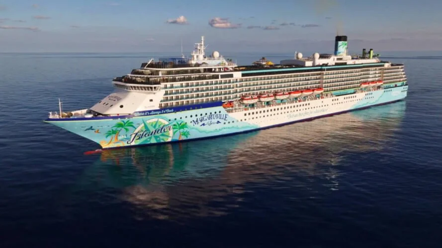 A large cruise ship with colorful island-themed artwork on the side, sailing on calm ocean waters.