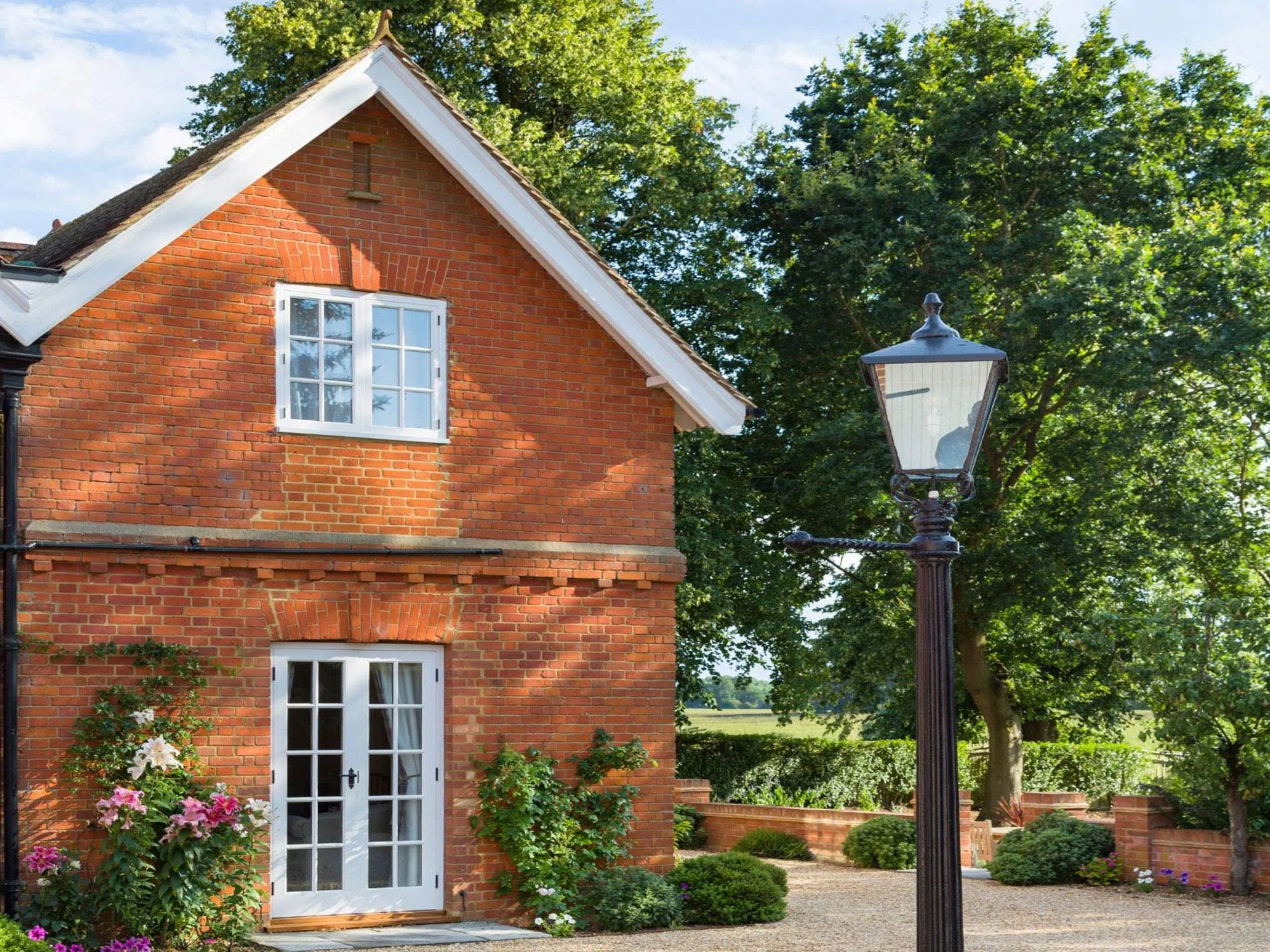 Red brick house at the edge of the countryside with mature trees