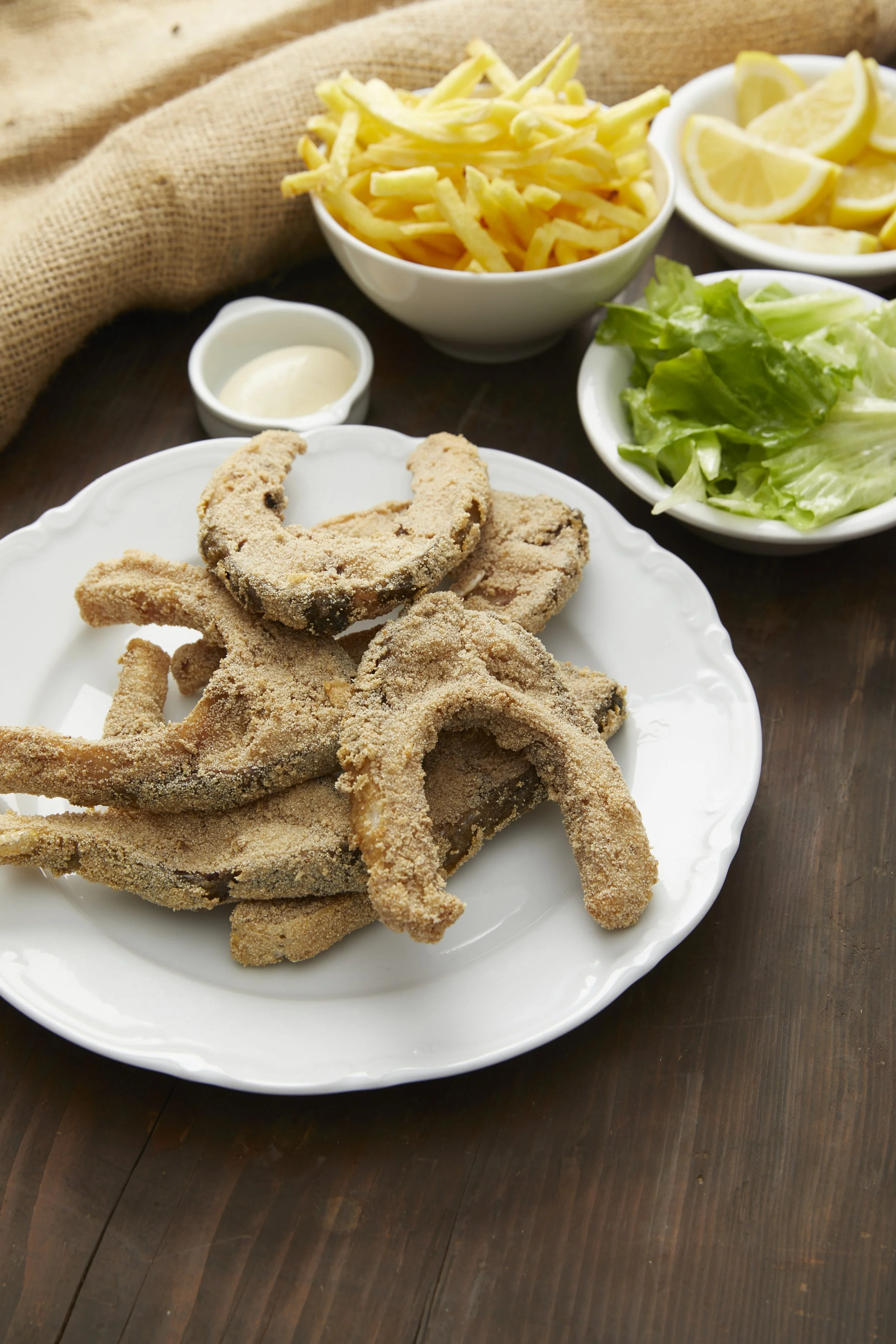 Assiette de friture de carpe avec salade, tranches de citron, frites, et sauce mayonnaise