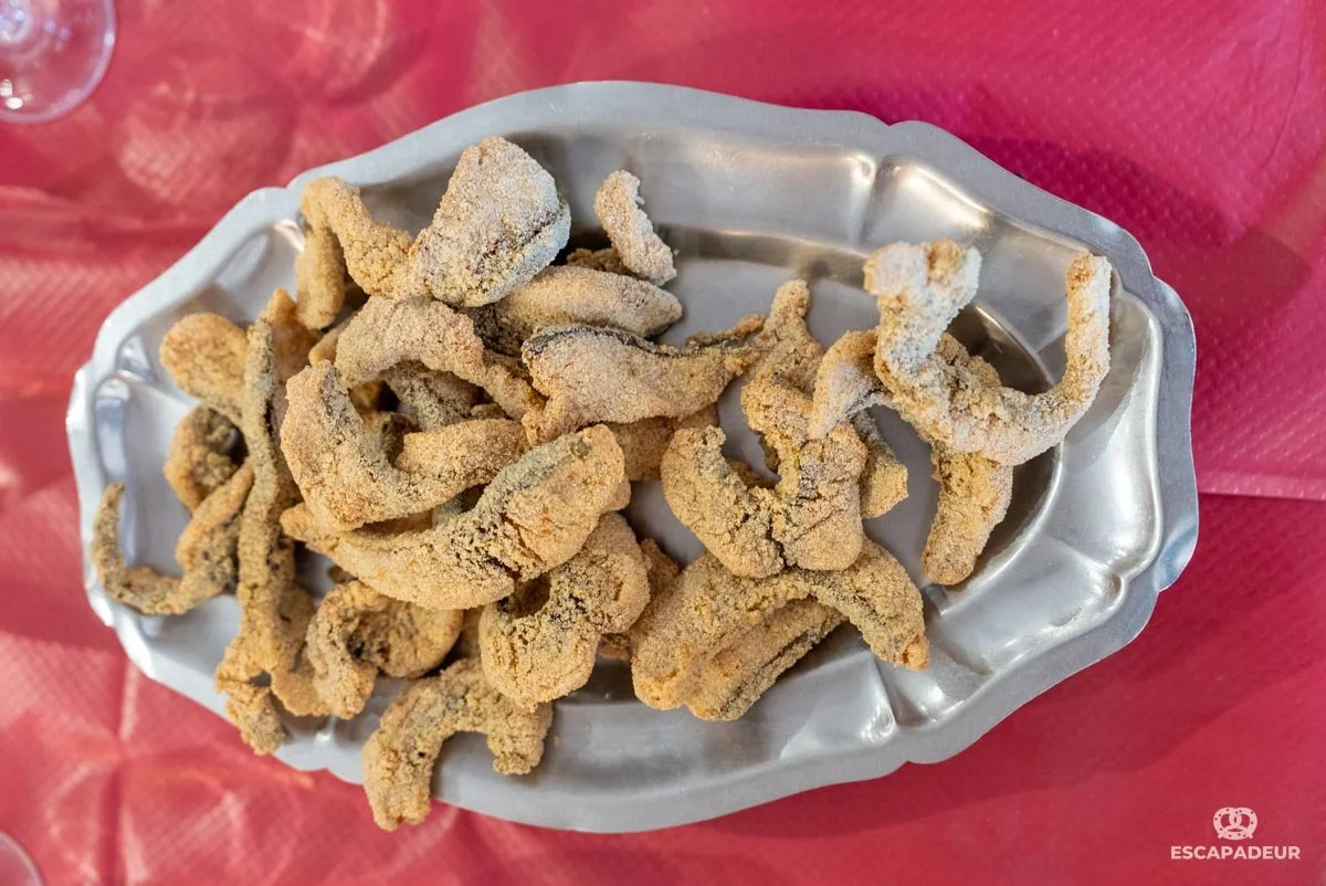 Filet de carpes dans un plat en aluminium, placé sur une table recouverte d'une nappe rouge.