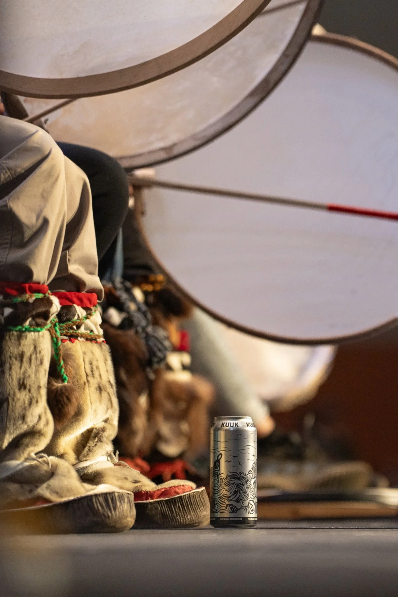 An array of traditional footwear and attire, a can with artistic black and white design, in an indoor setting.