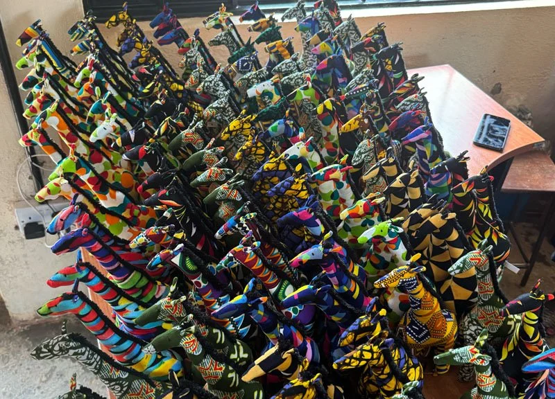 Colorful African fabric animals, including giraffes and elephants, arranged on a table.
