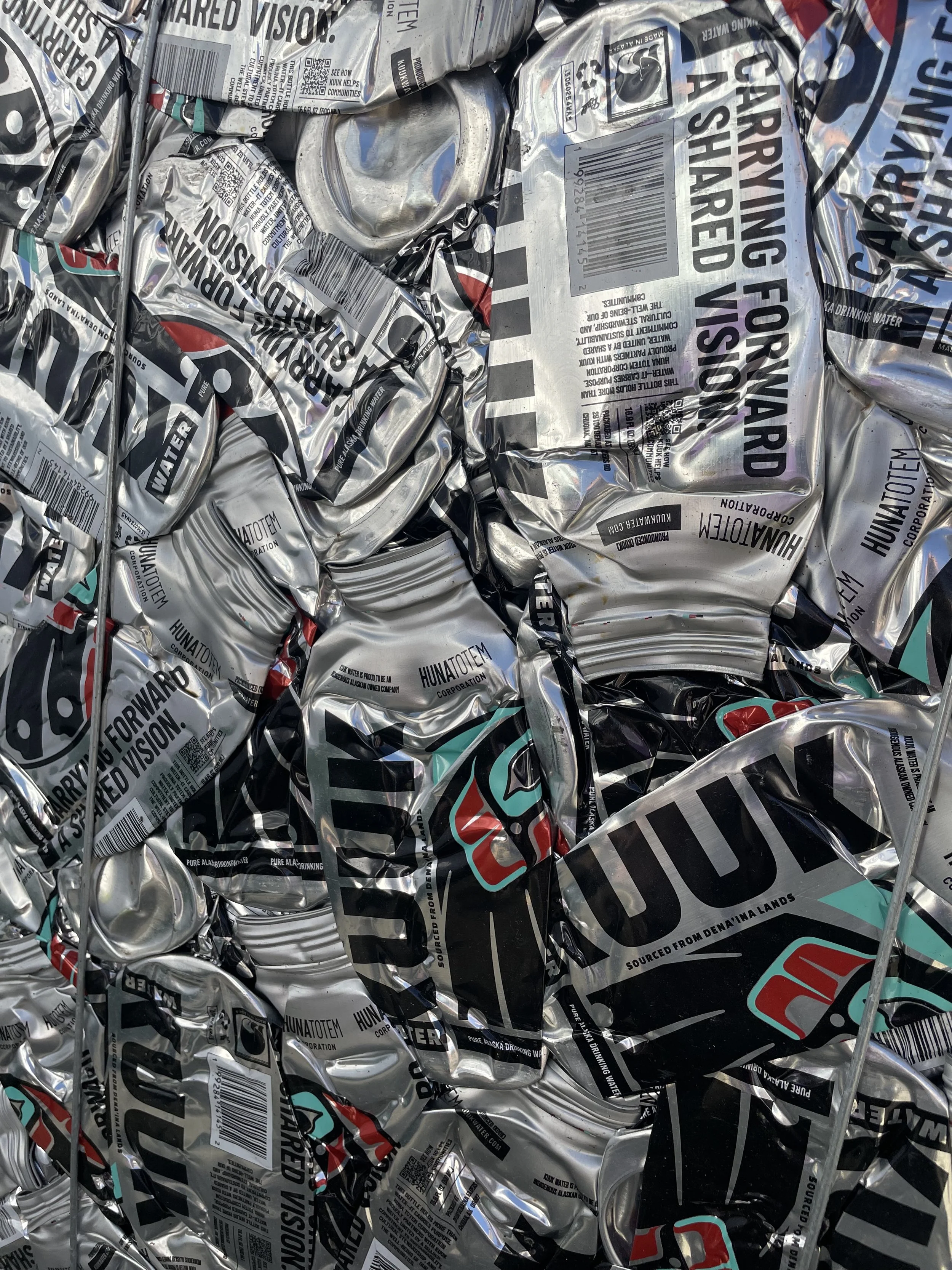 Crushed cans of water made of aluminum, labeled with text that includes hazard warnings and brand information.