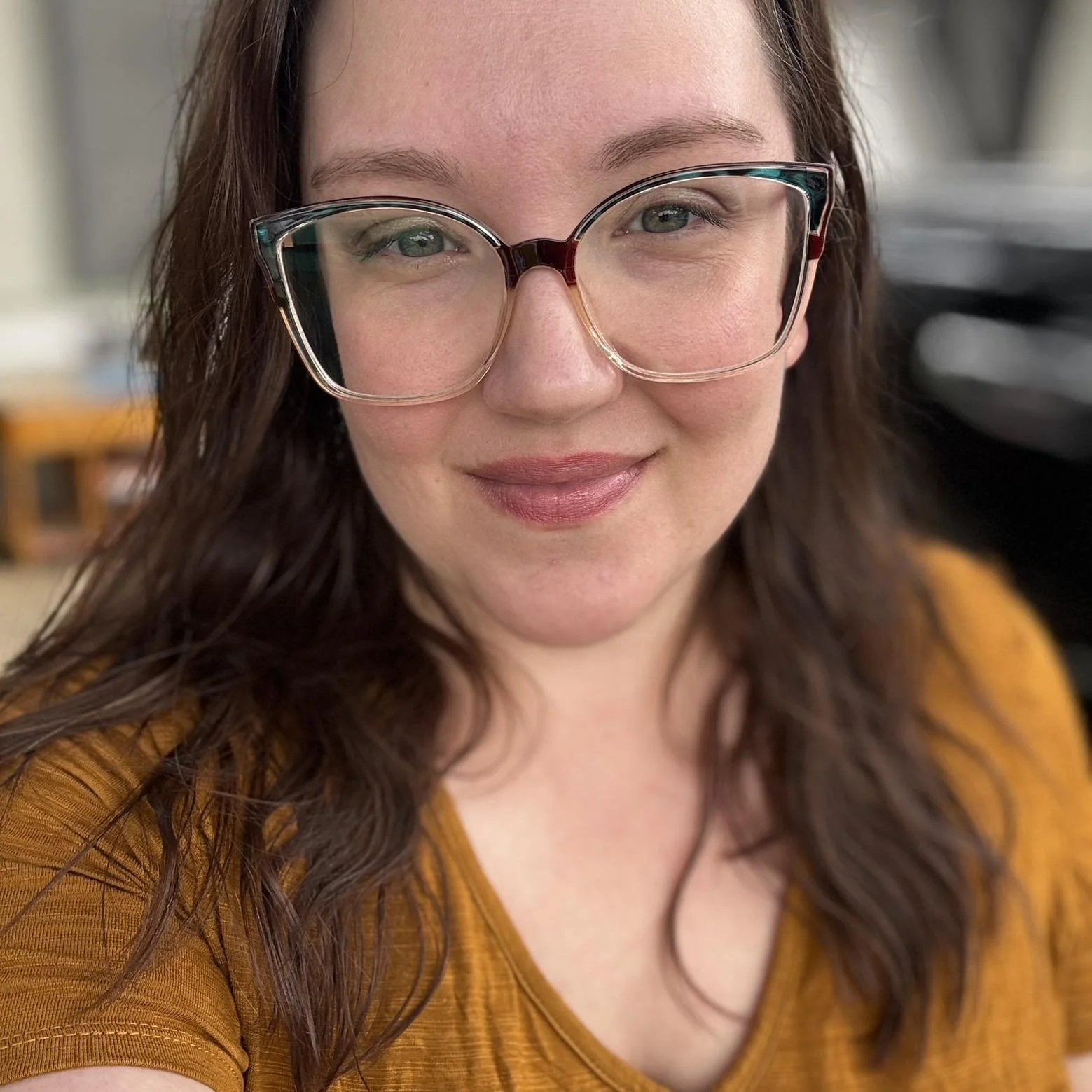 A close-up image of Haleigh in a yellow shirt, smiling warmly with a calm expression.