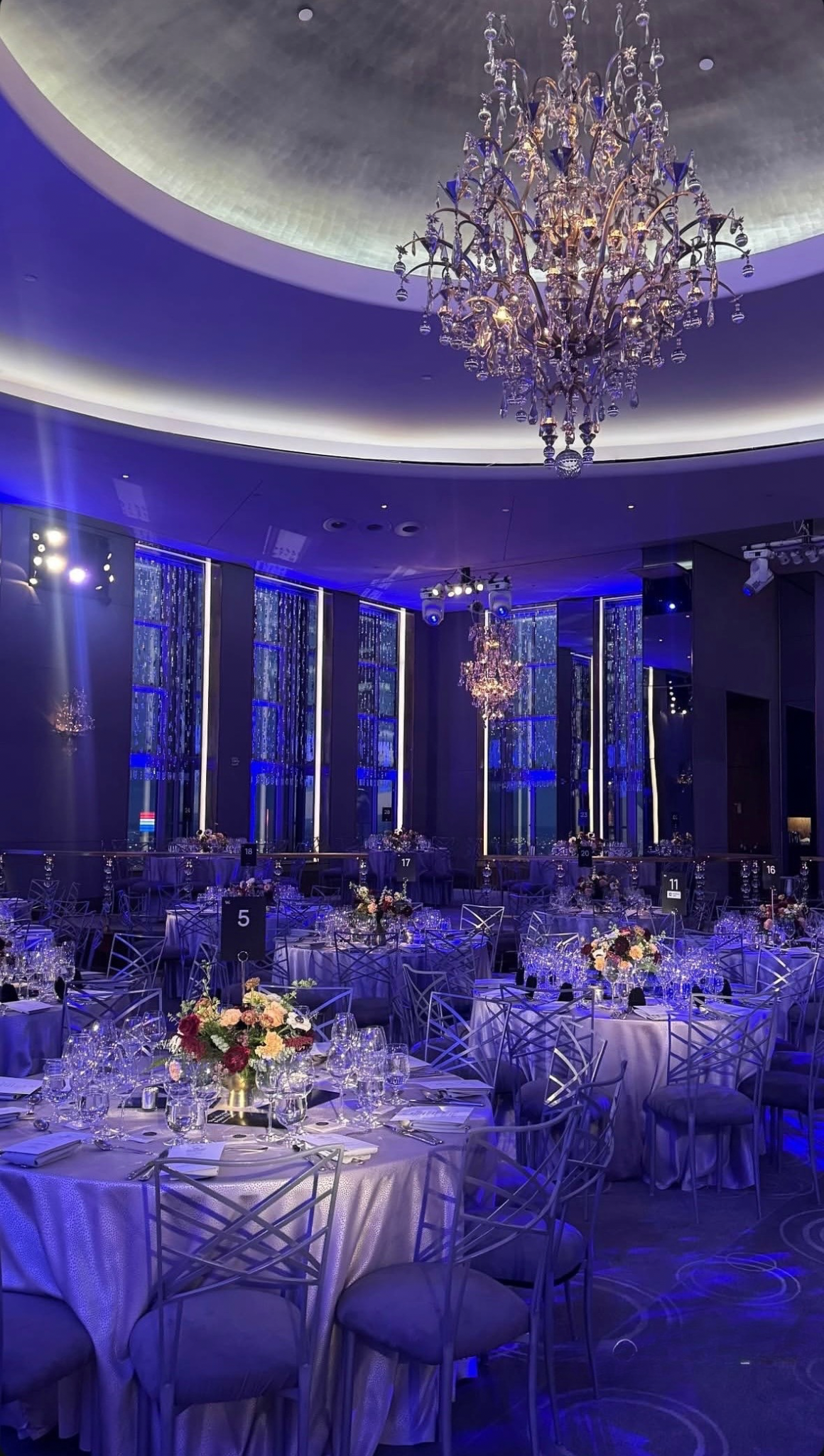 Elegant ballroom wedding with blue uplighting and tall floral centerpieces